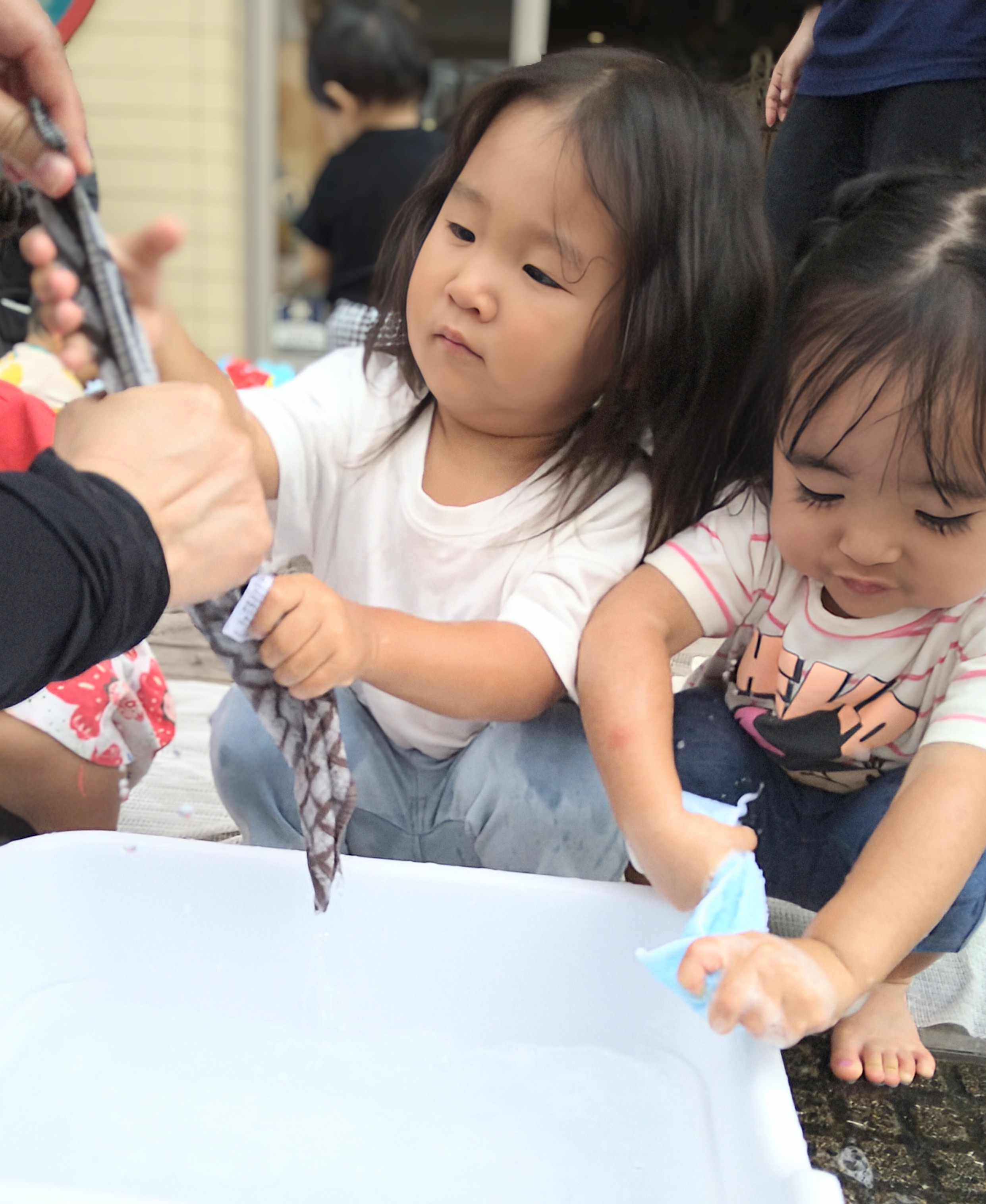 濡れた布を両手で握り水を落とす子どもたち