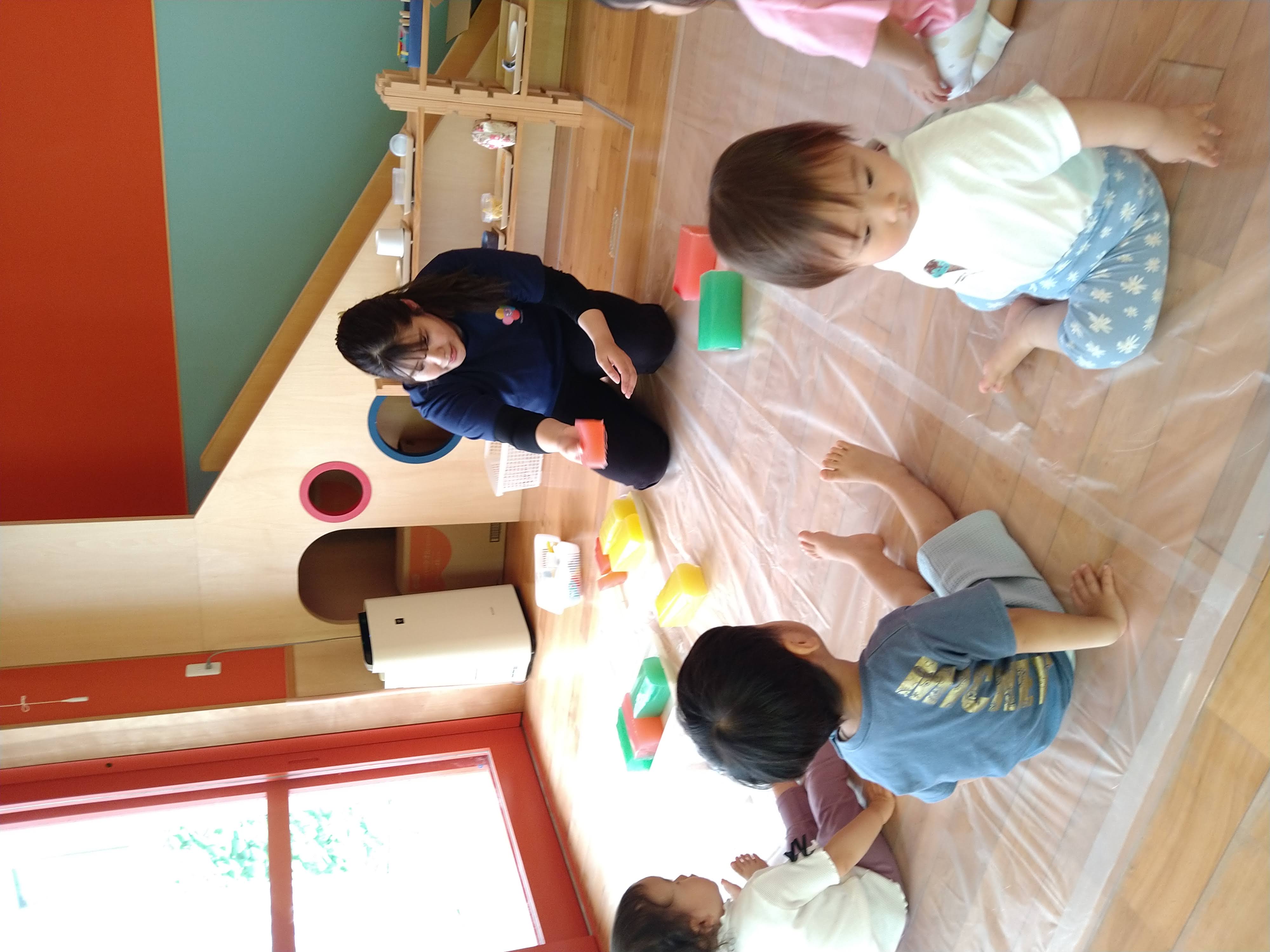 保育士が色とりどりの寒天を見せ、子どもたちが見つめる様子