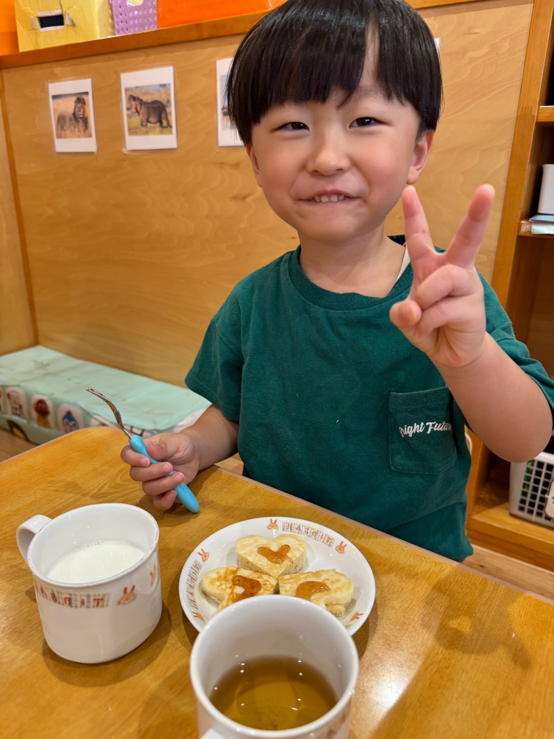 ハート形のおやつを前に笑顔で指を立てる子ども