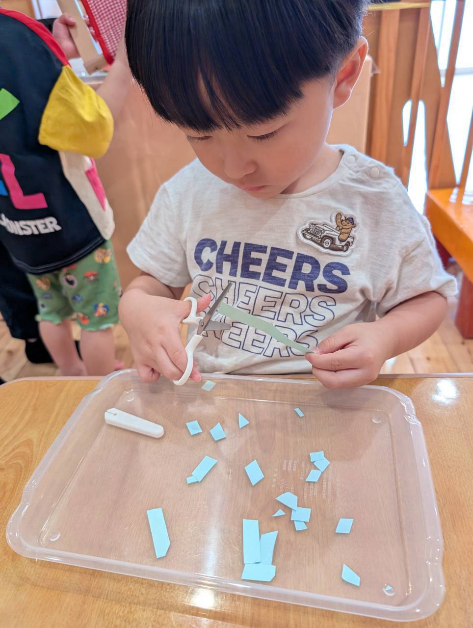 片手で紙を持ちはさみを開閉する子ども