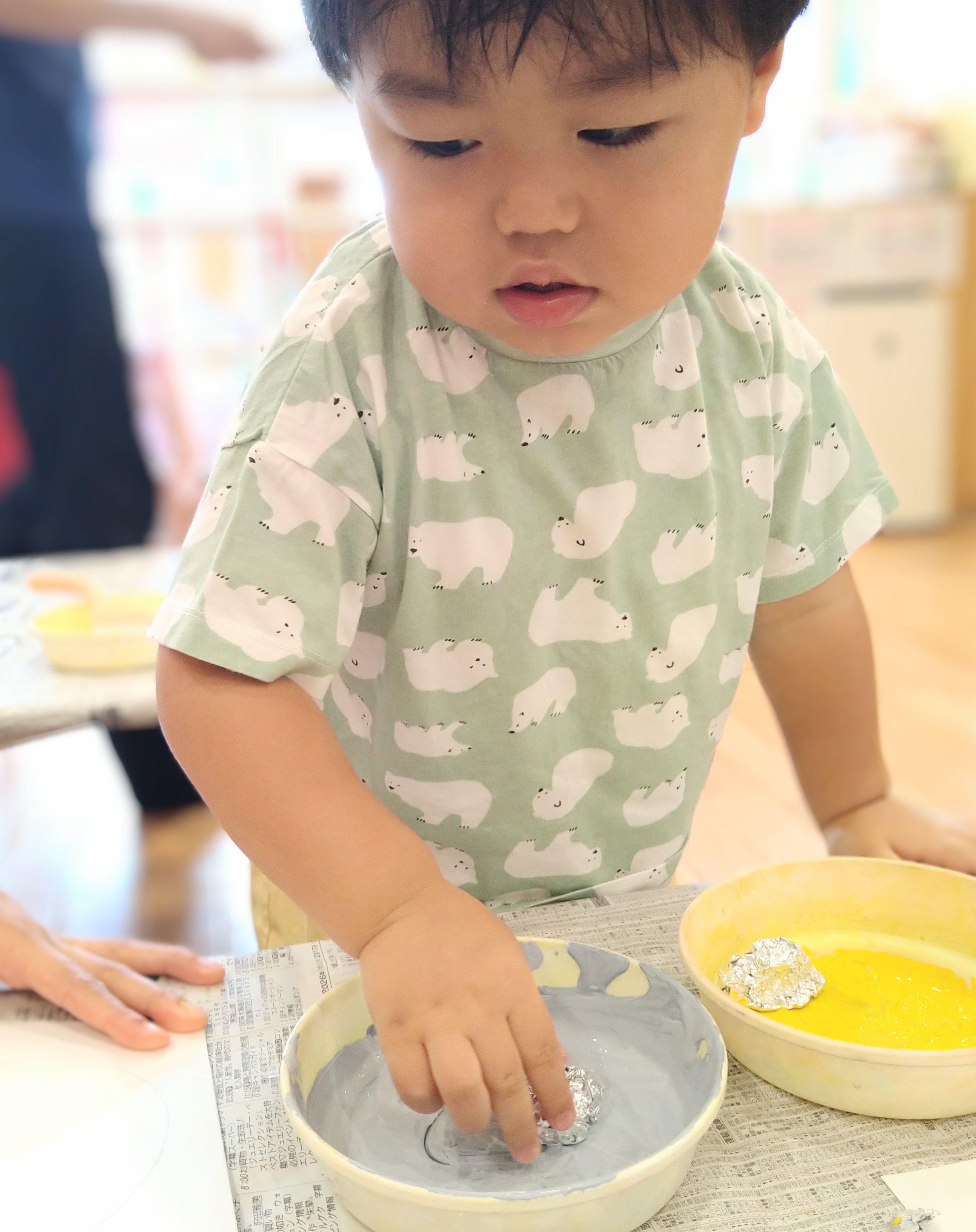 丸めたアルミホイルを持って絵の具につける子ども