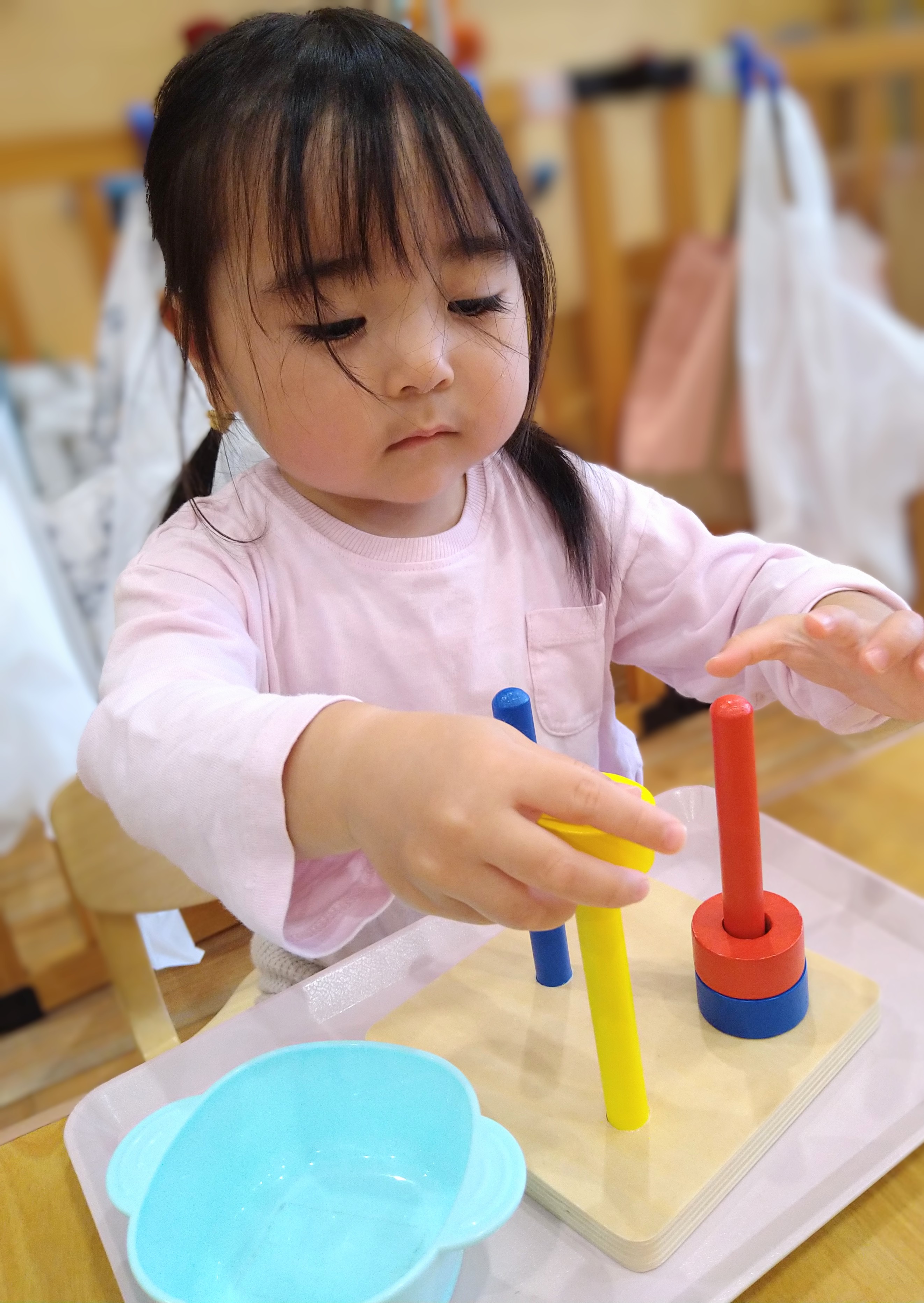 色の異なる輪を棒へ通す子ども
