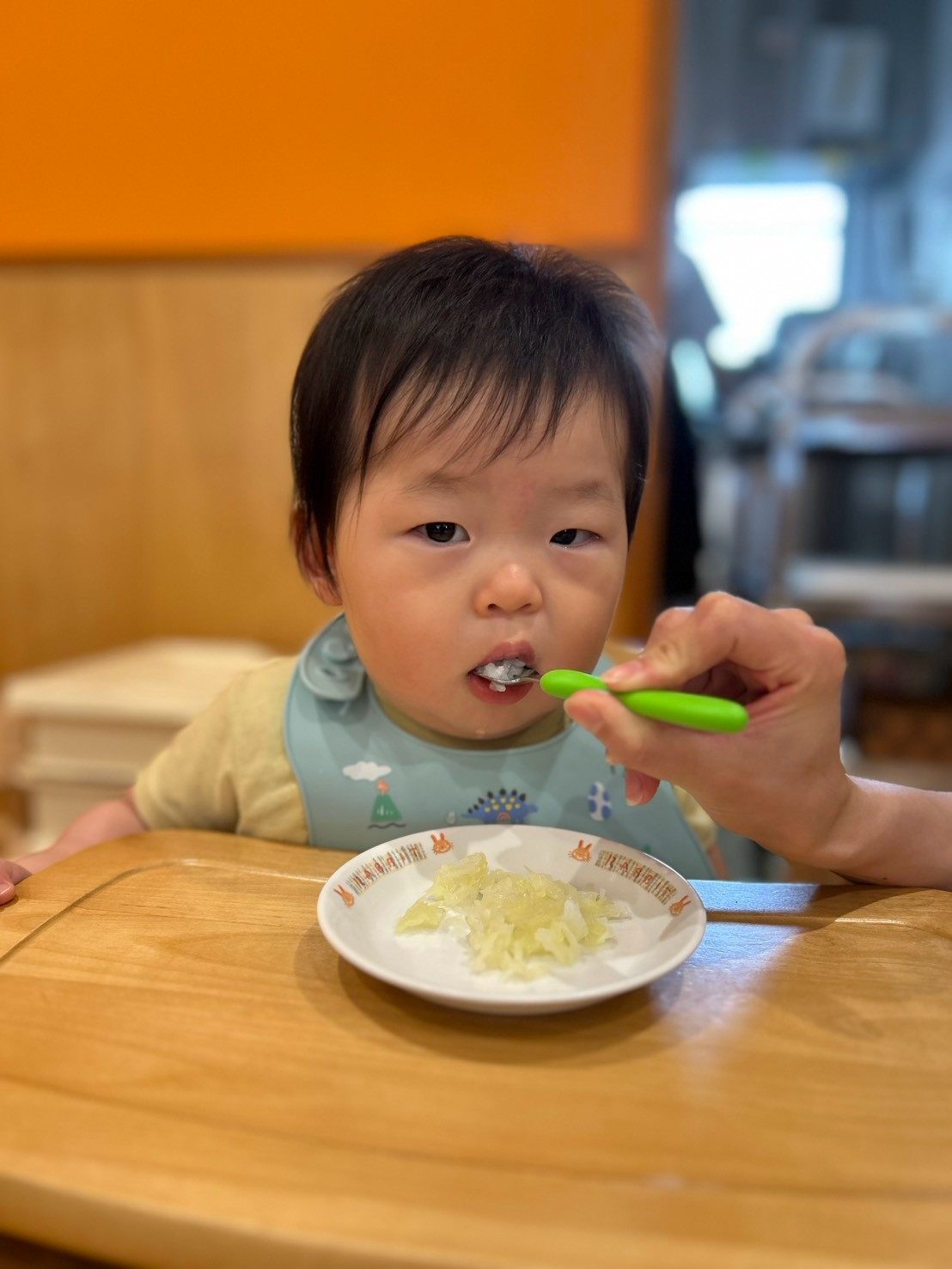 保育士の介助で給食をひと口味わう様子