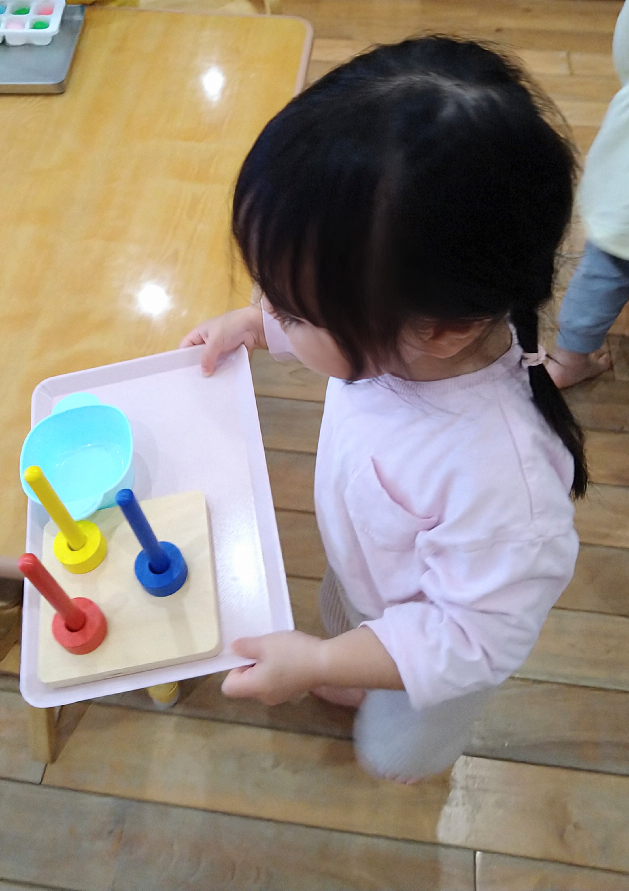 教具を載せたトレーを両手で運ぶ子ども
