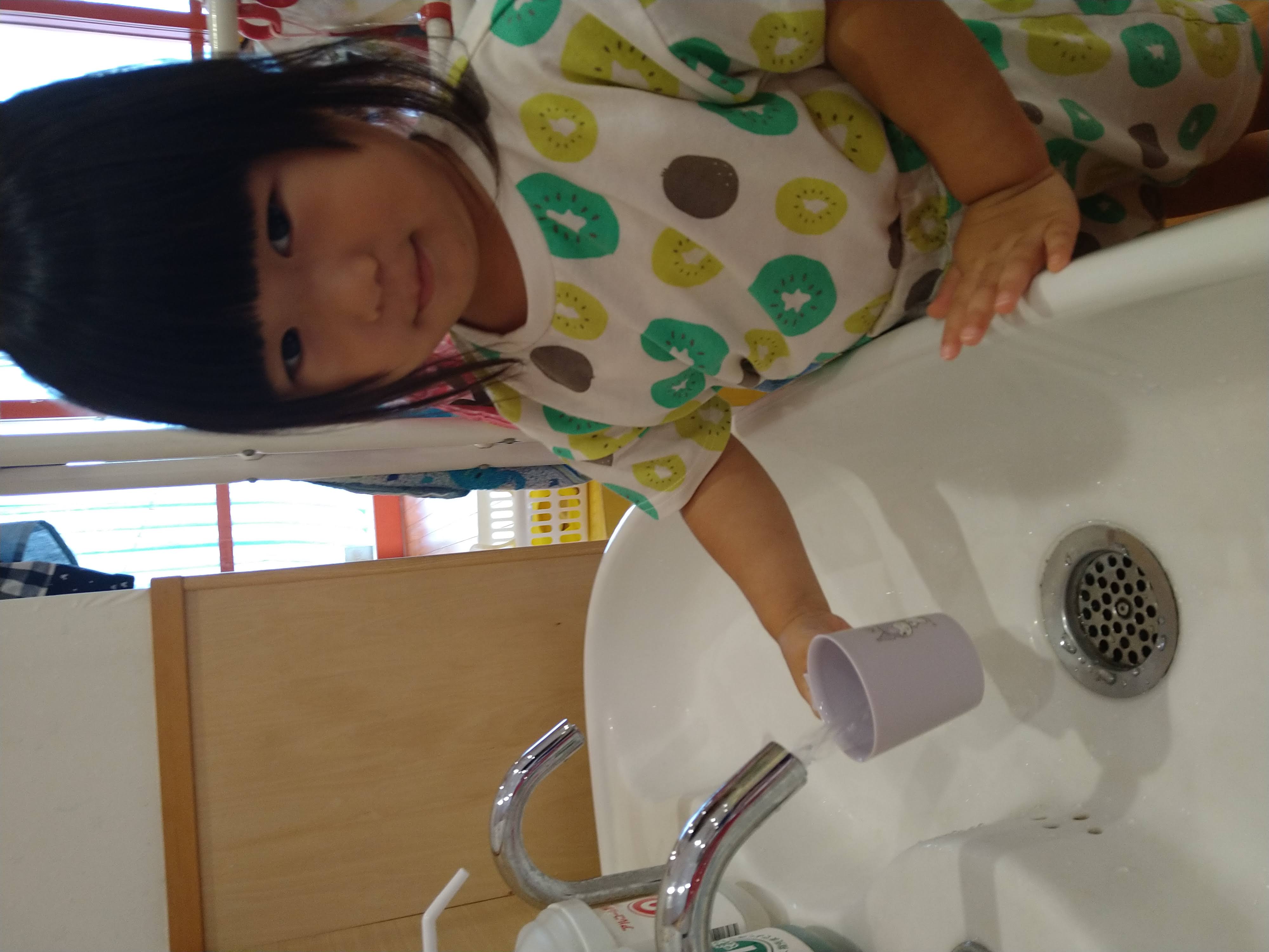 洗面台でコップに水を入れる子ども
