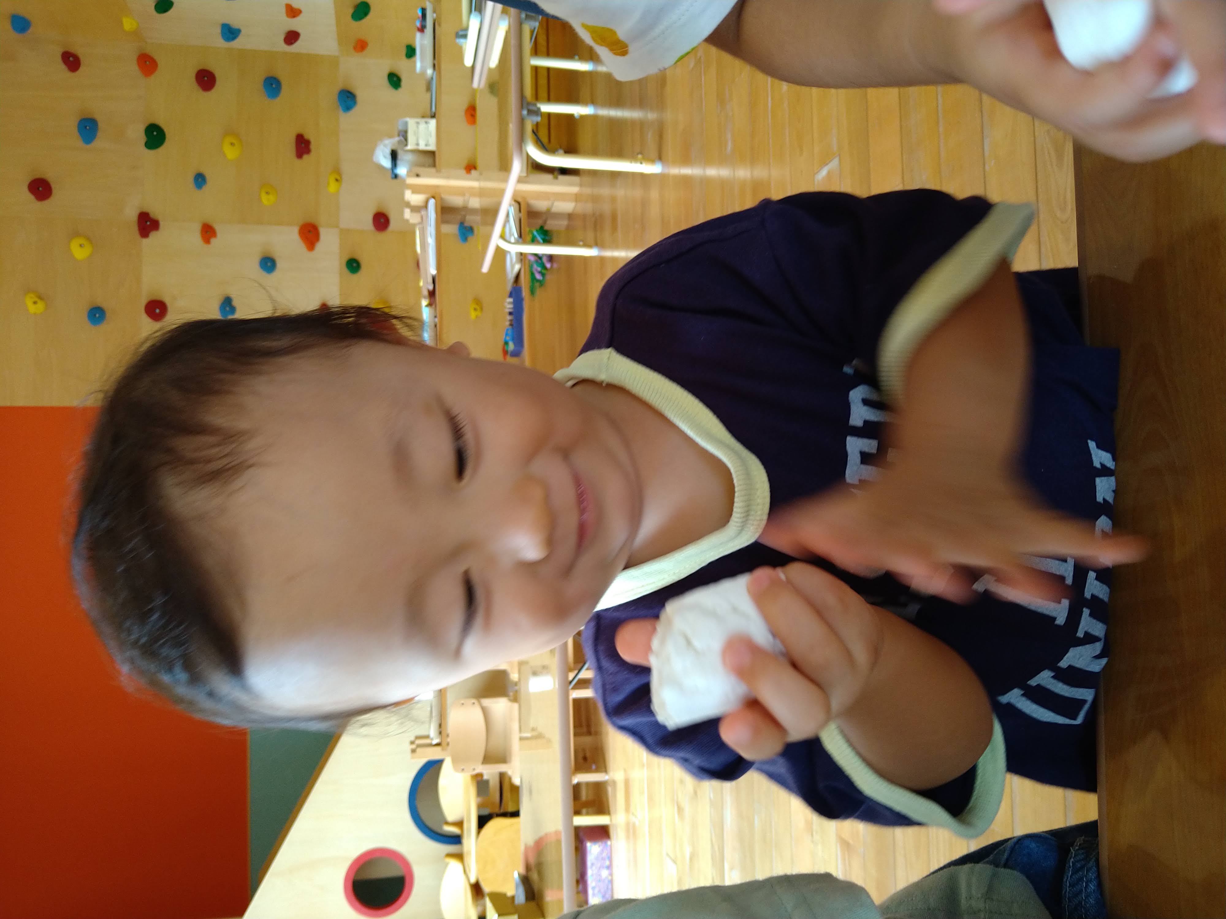 丸めた白いお団子を手に持って見つめる子ども