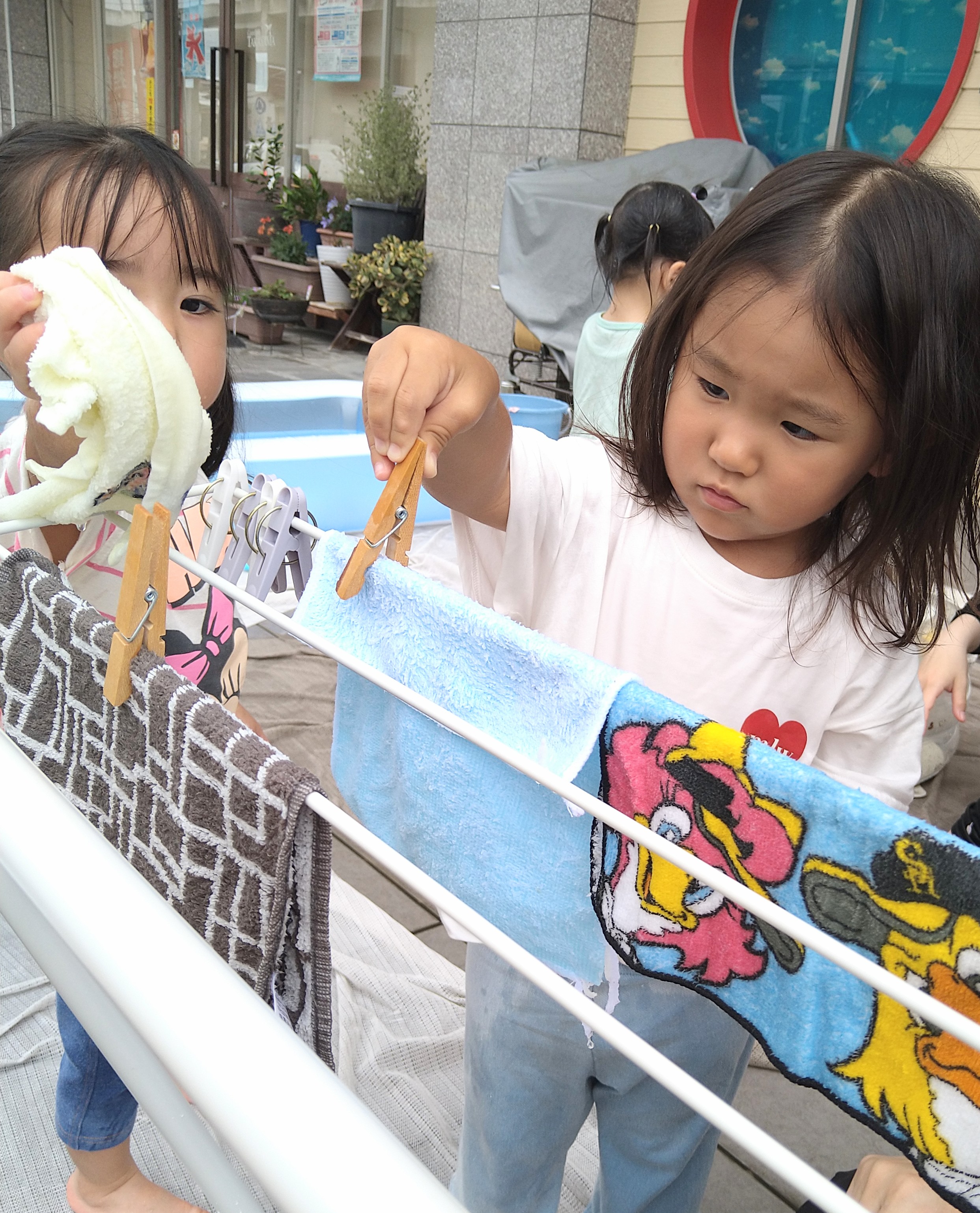 洗濯ばさみを使ってタオルを物干しへ留める子ども