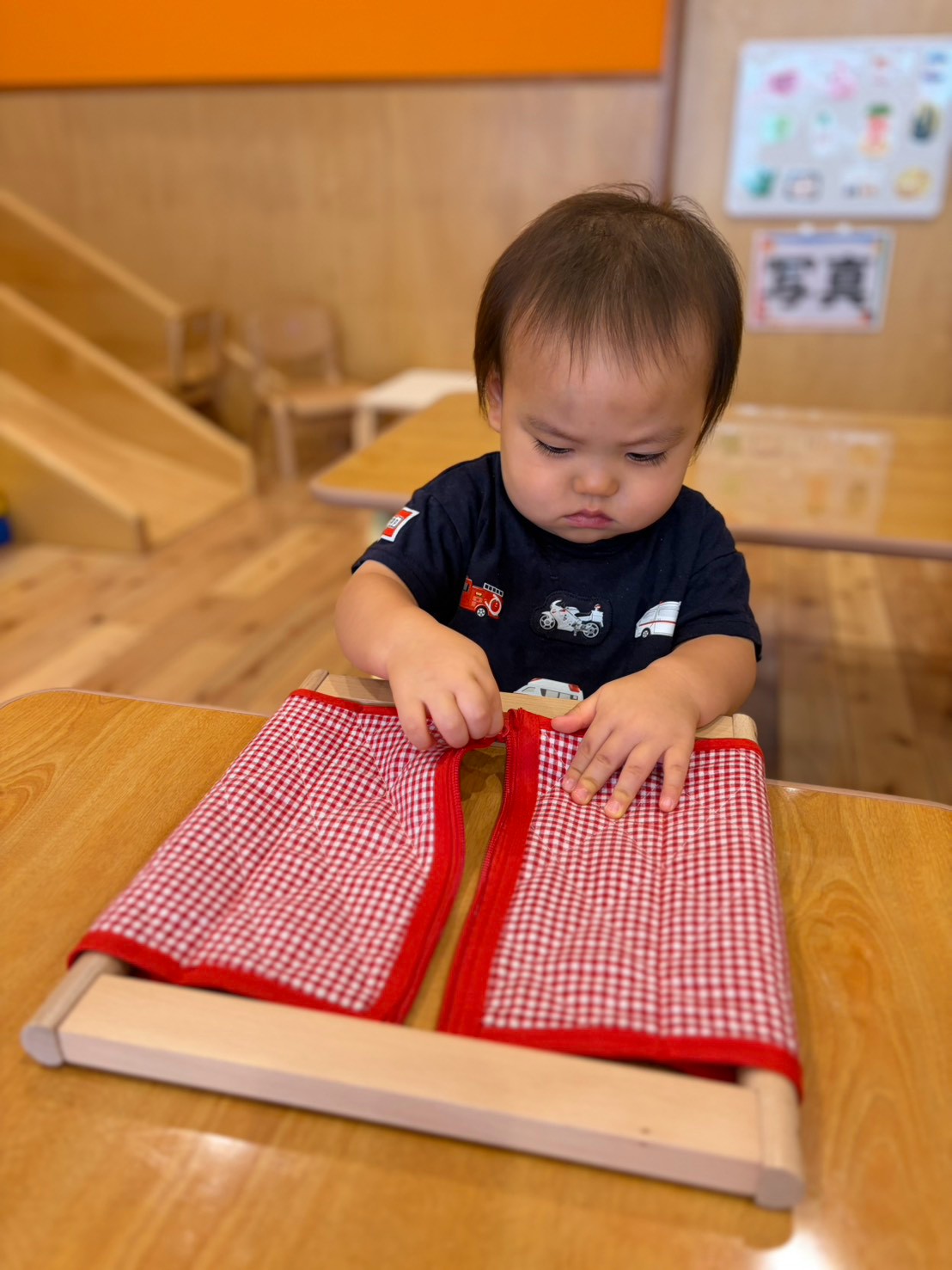片手で布を押さえながらチャックを動かす子ども