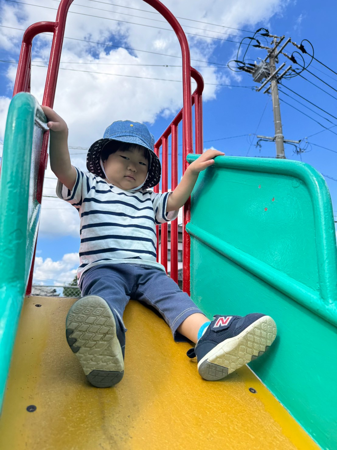 すべり台の手すりにつかまり姿勢を整える子ども