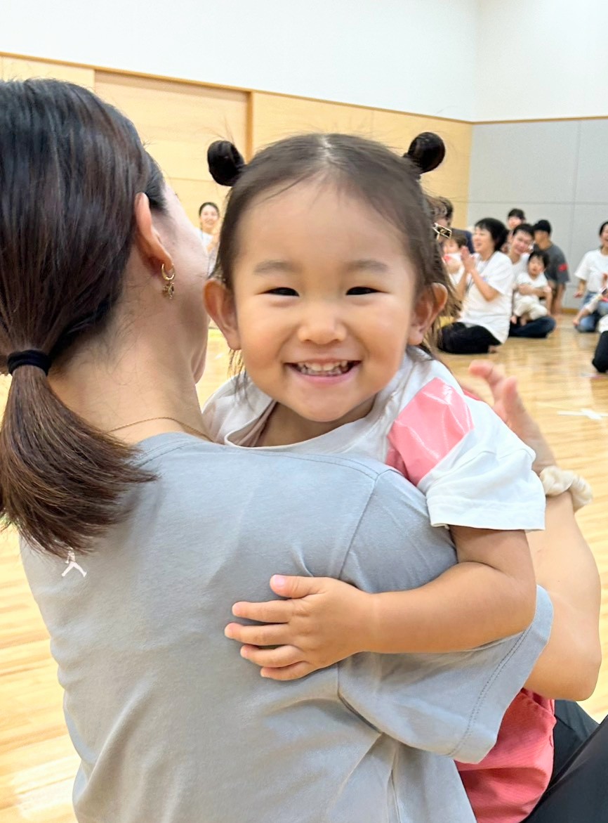 保護者に抱きしめられて笑顔を見せる子ども
