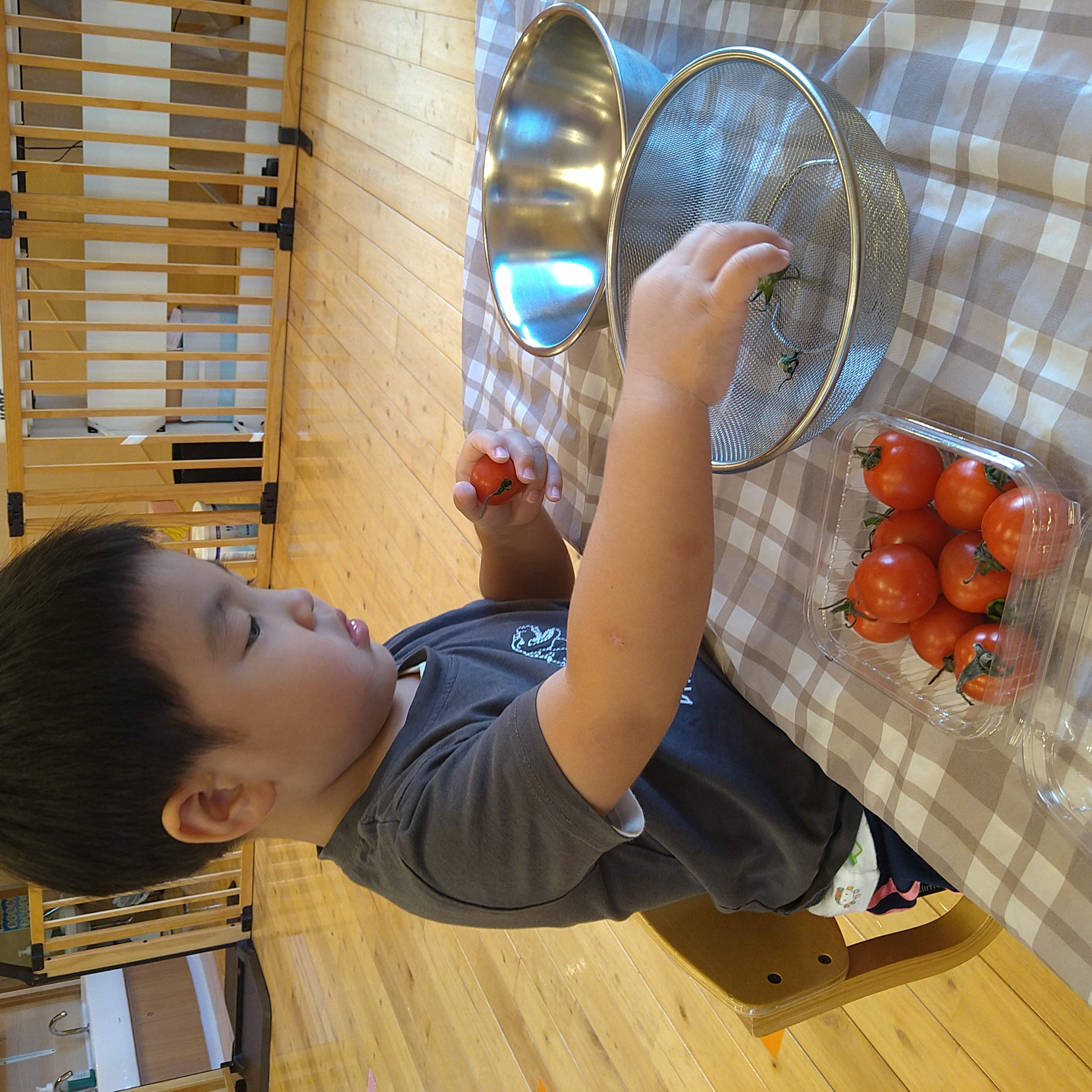 外したトマトのへたをざるへ入れる子ども