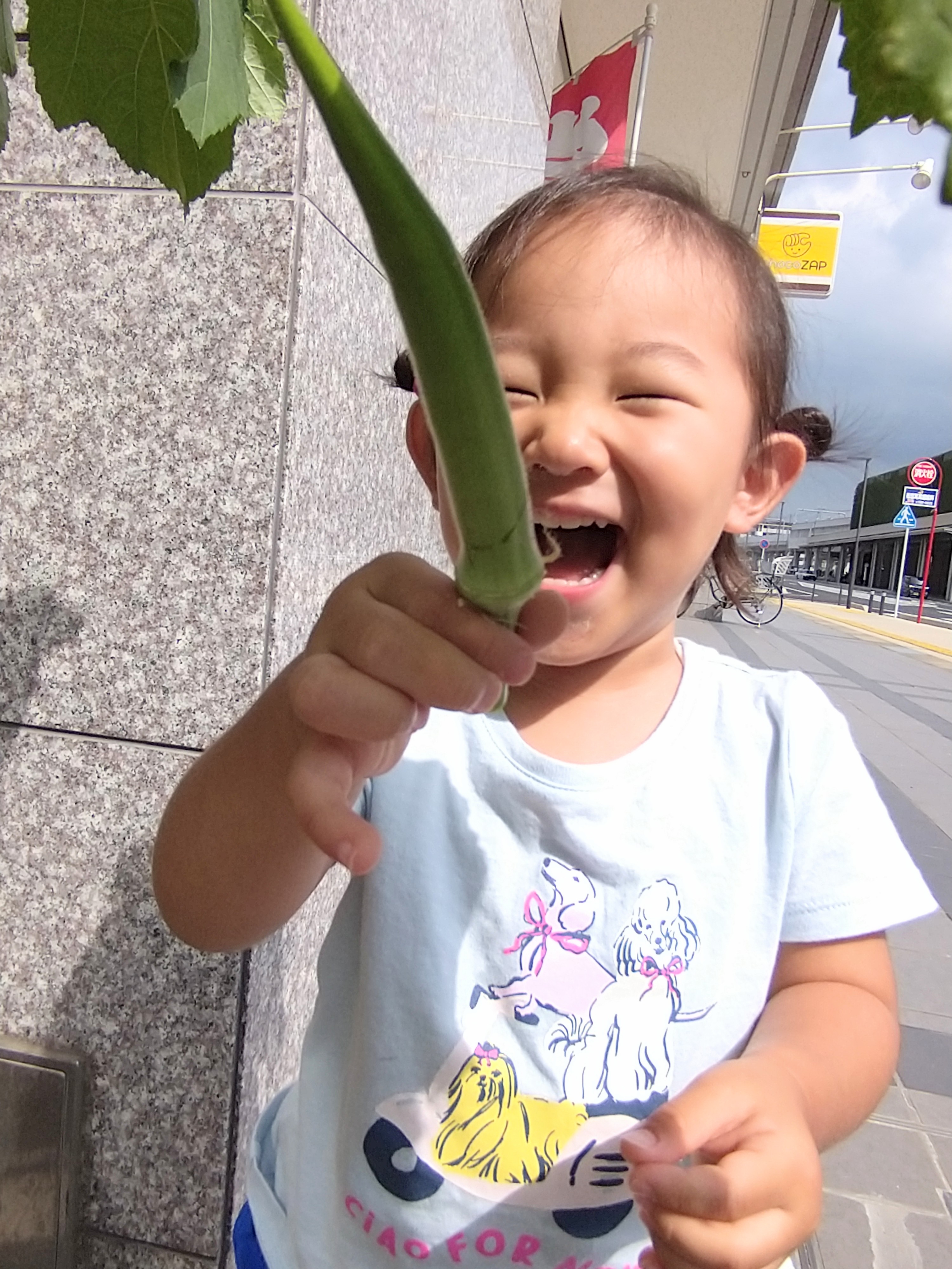収穫したオクラを手に笑顔を見せる子ども