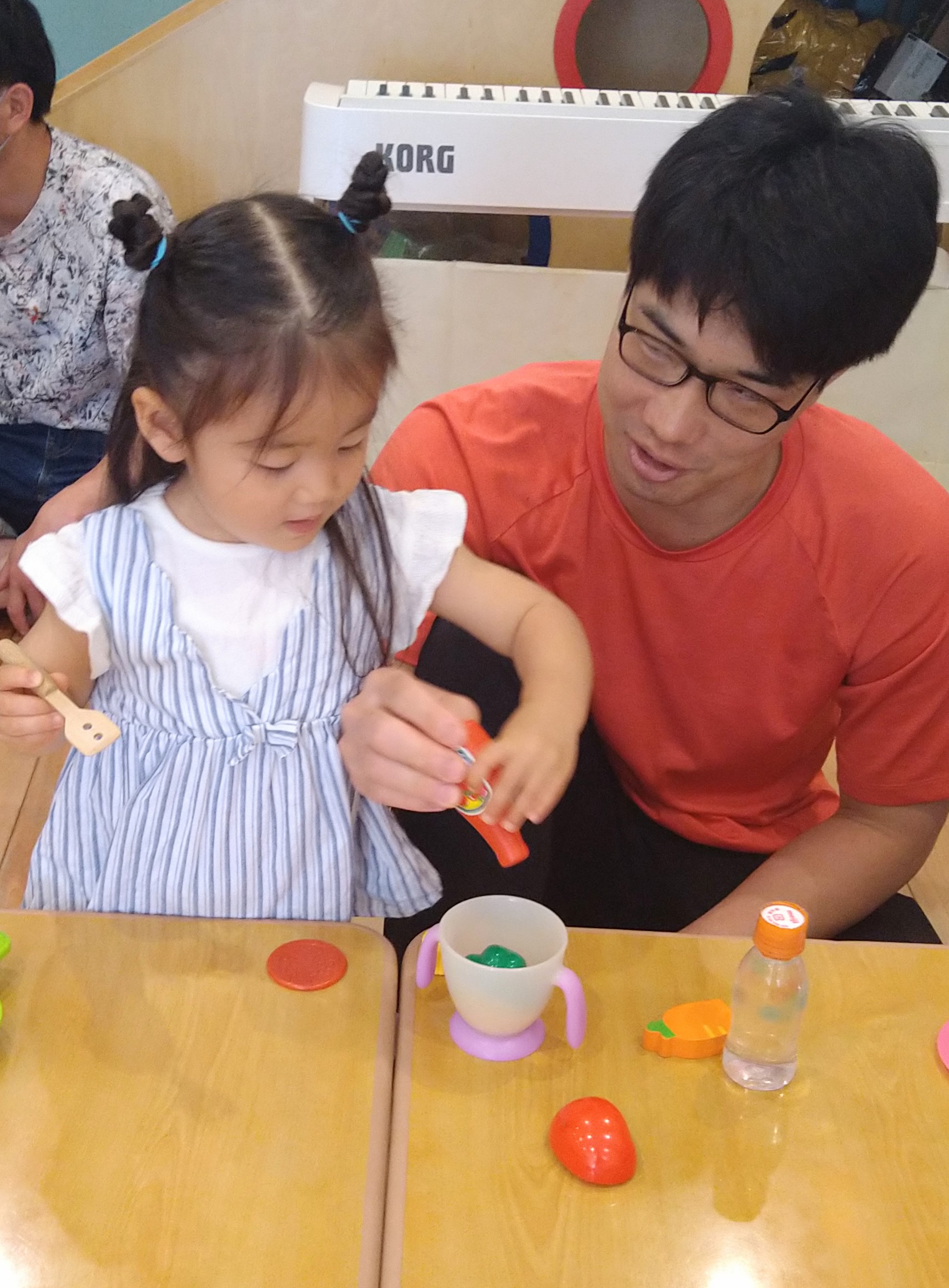 保護者に見守られながらままごとの道具を使う子ども