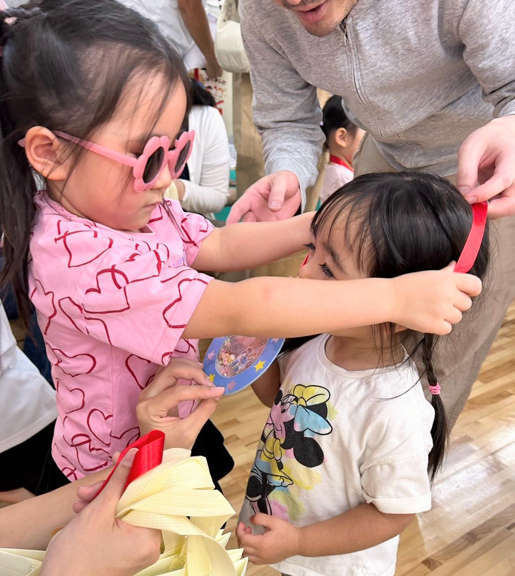 相手の首元へ赤いリボンのメダルを掛けようとする子ども