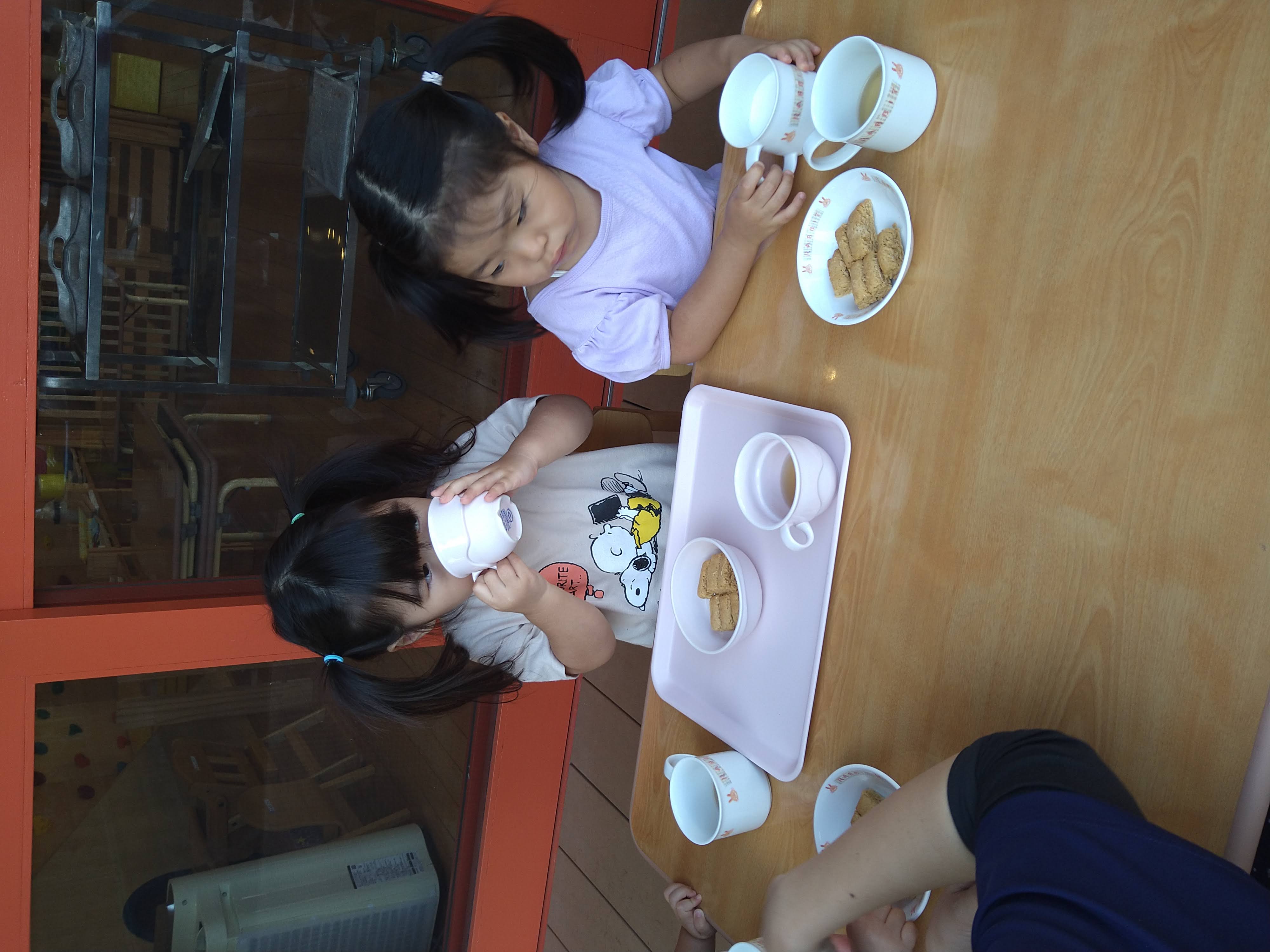 コップを両手で持って飲む子ども