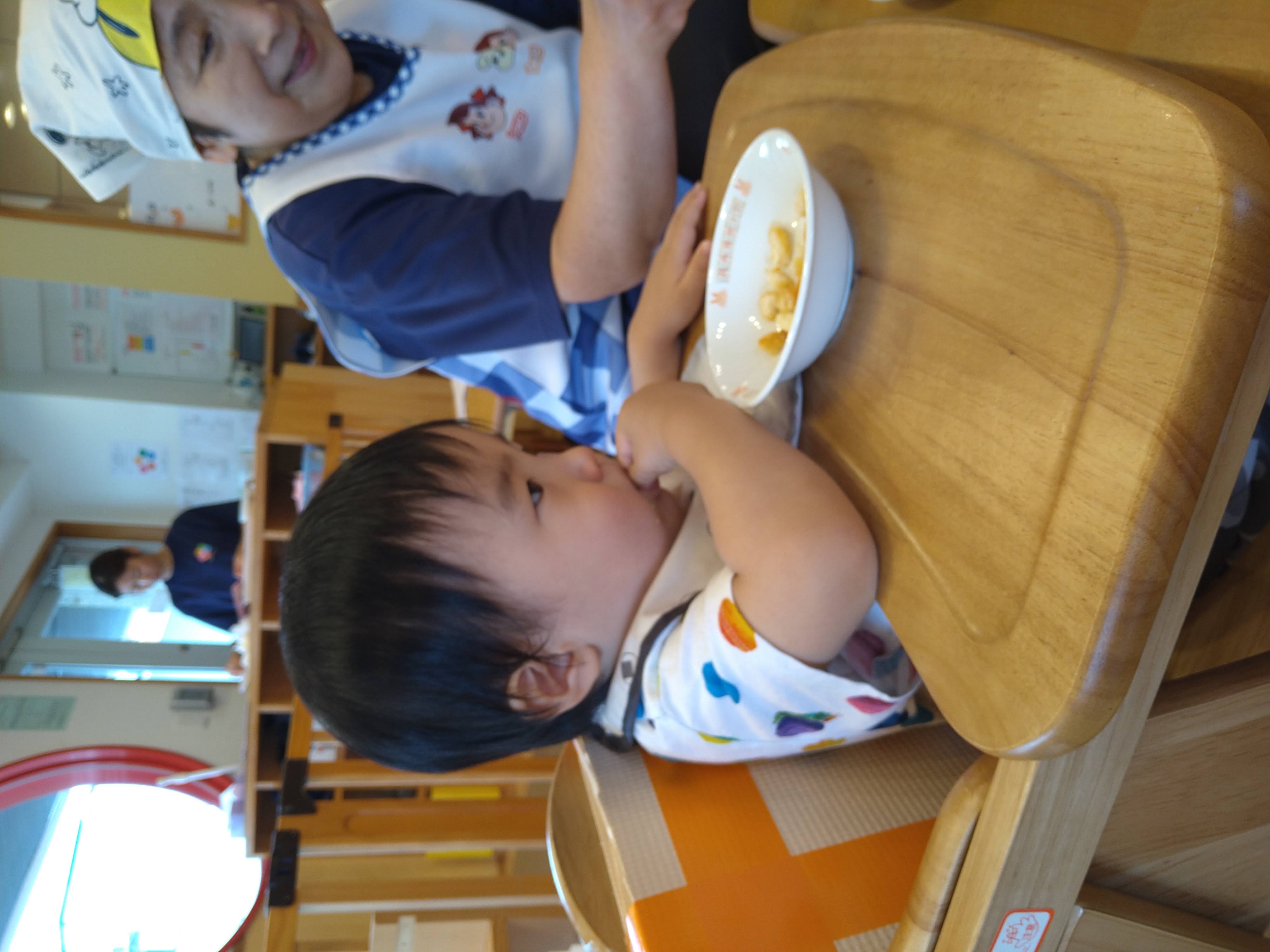 保育士のそばで自分の手を使って食べる子ども