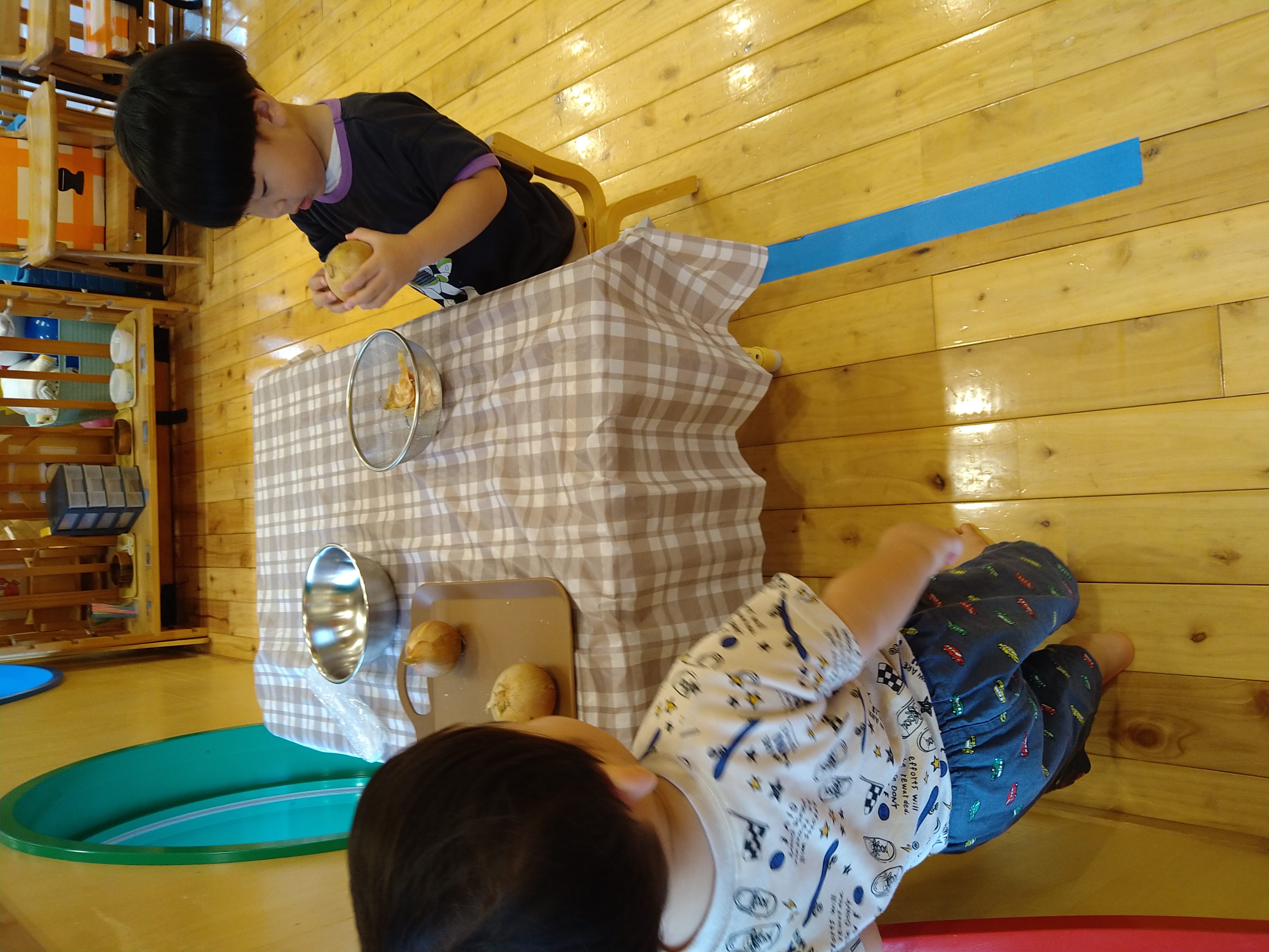 片手で玉ねぎを持ちもう片方の手で皮をむく子ども
