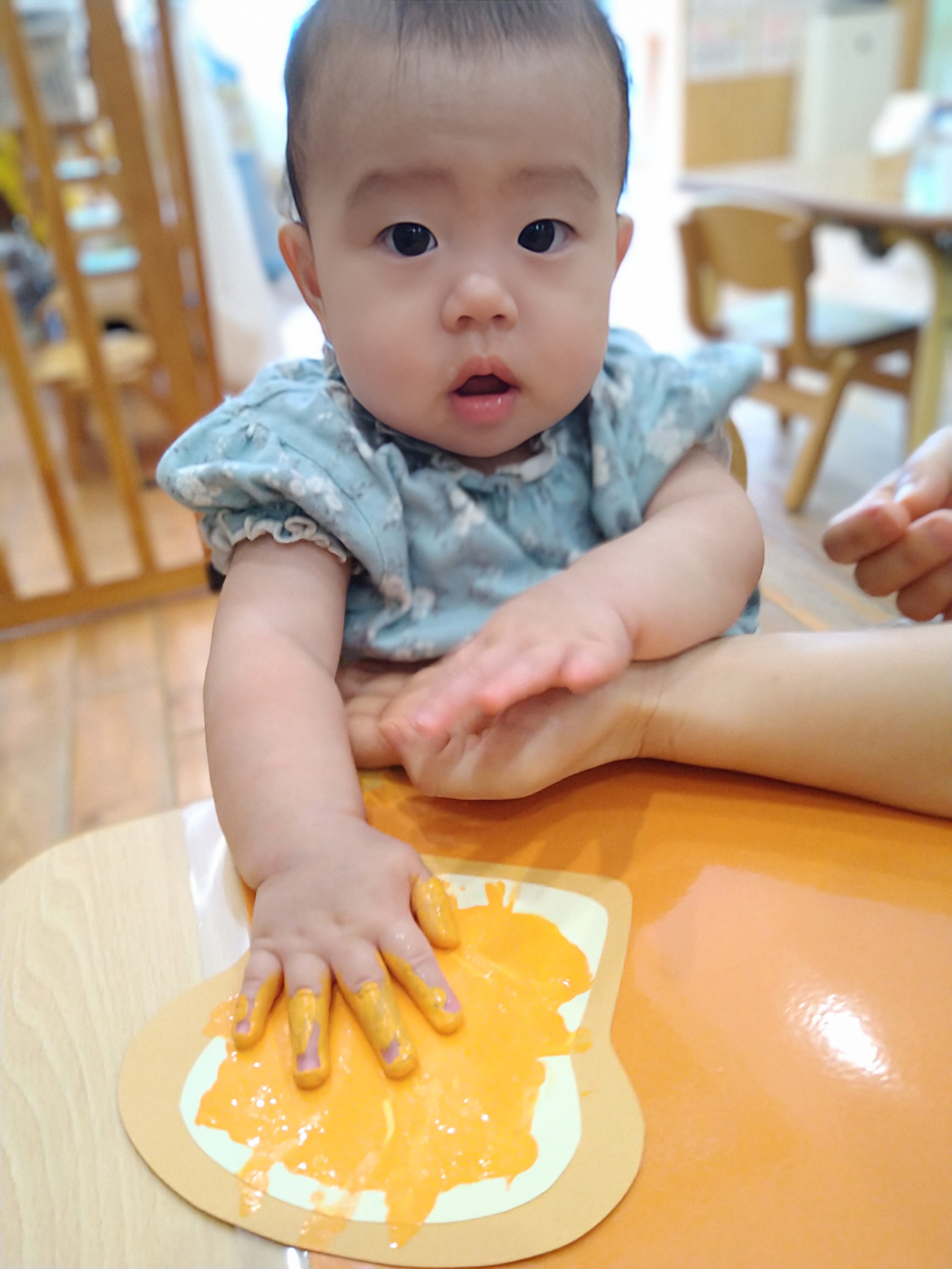 パン形の台紙へ手のひらで絵の具を広げる子ども
