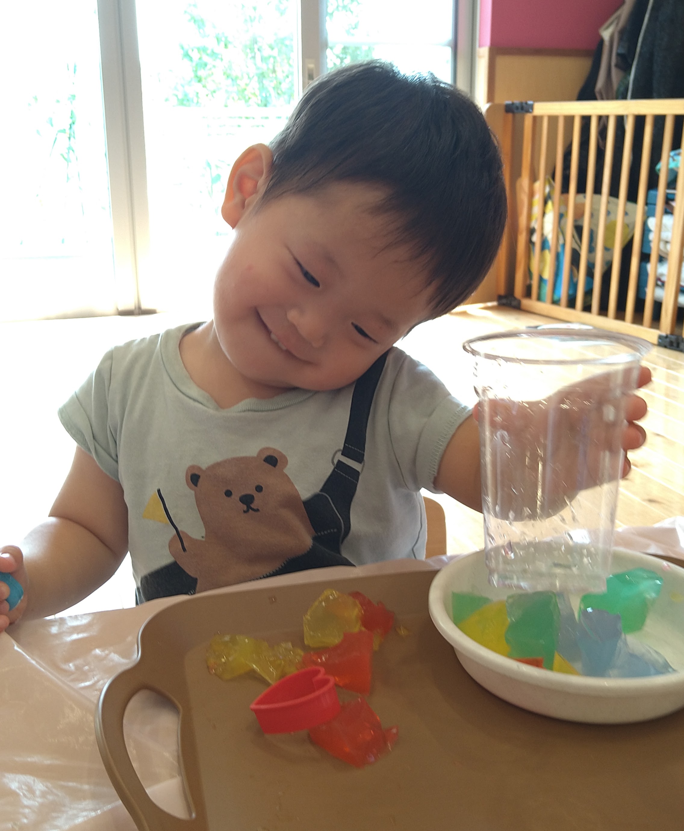 色寒天を容器と道具で扱いながら感触を確かめる子ども