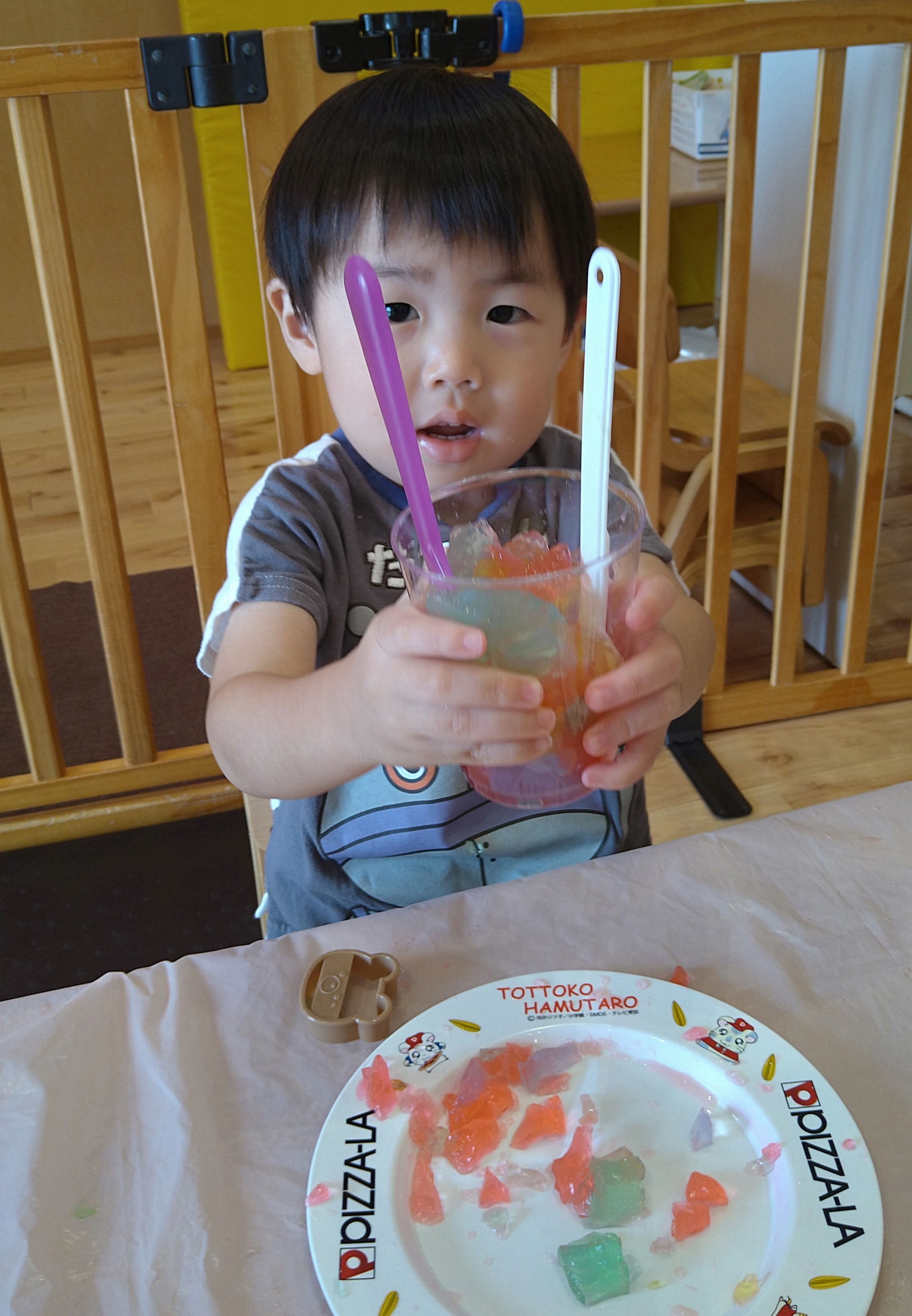 色寒天を入れた透明な容器を両手で見せる子ども