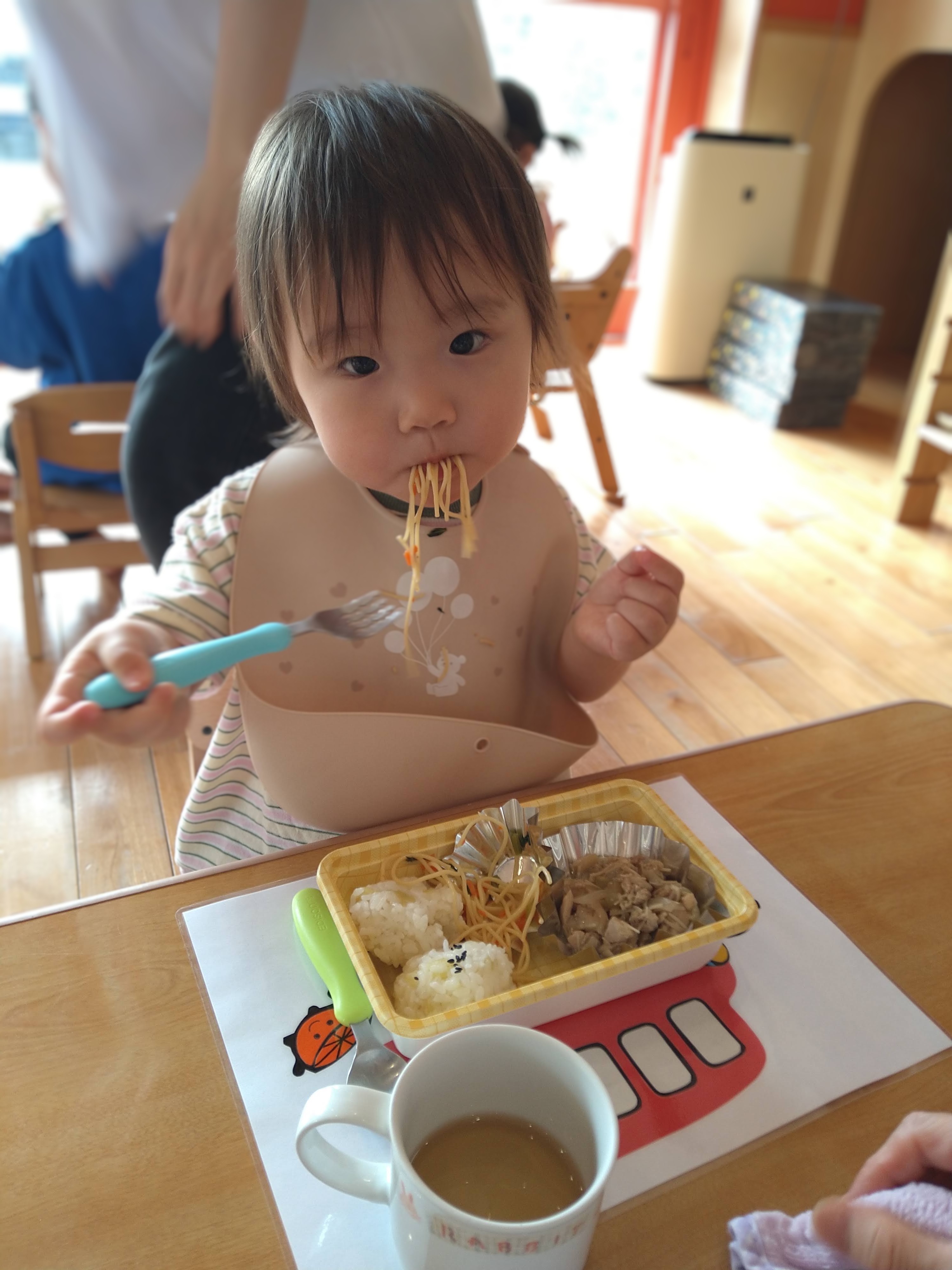 フォークで麺を口へ運ぶ子ども