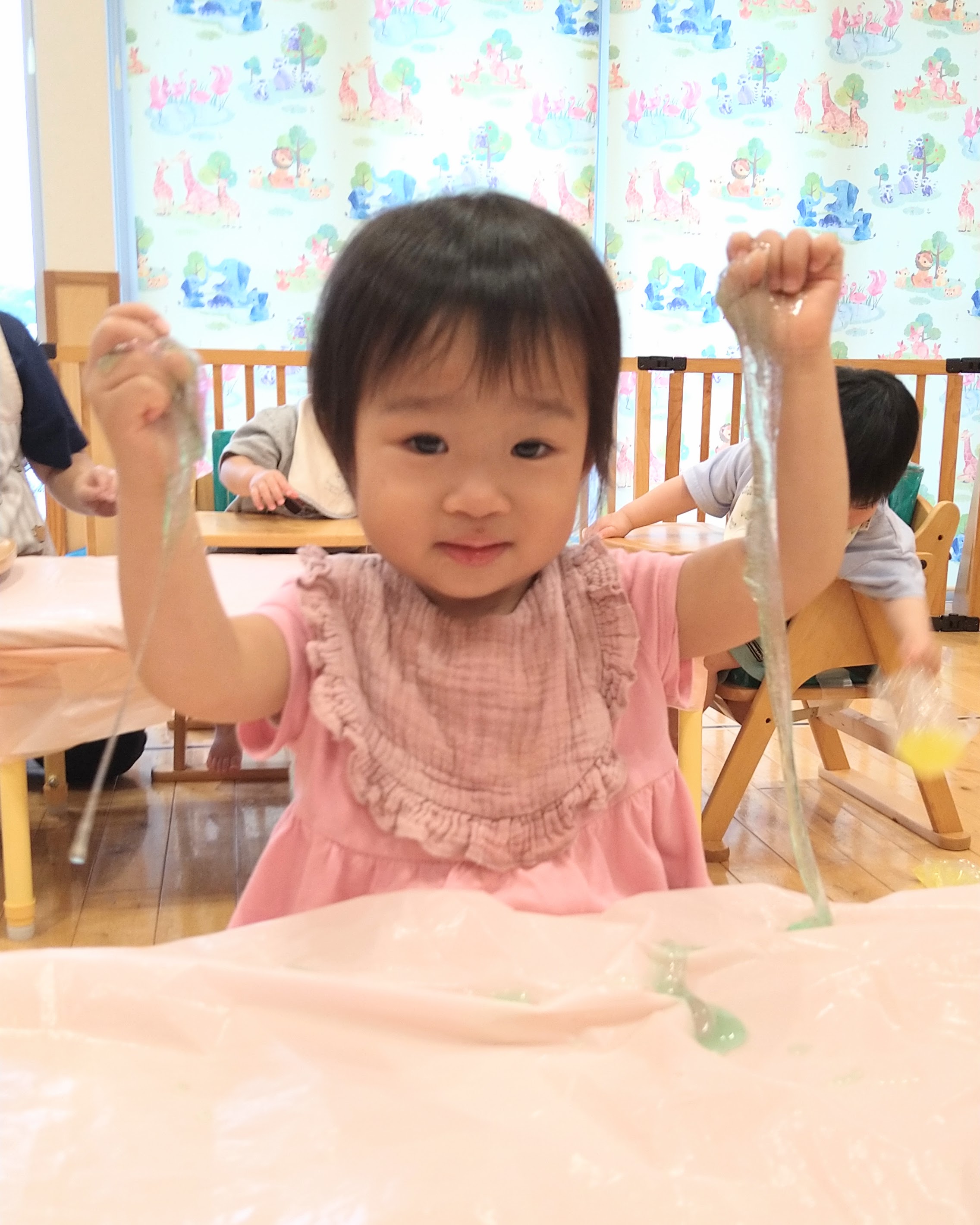 両手で持ち上げたスライムが長く伸びる様子を楽しむ子ども