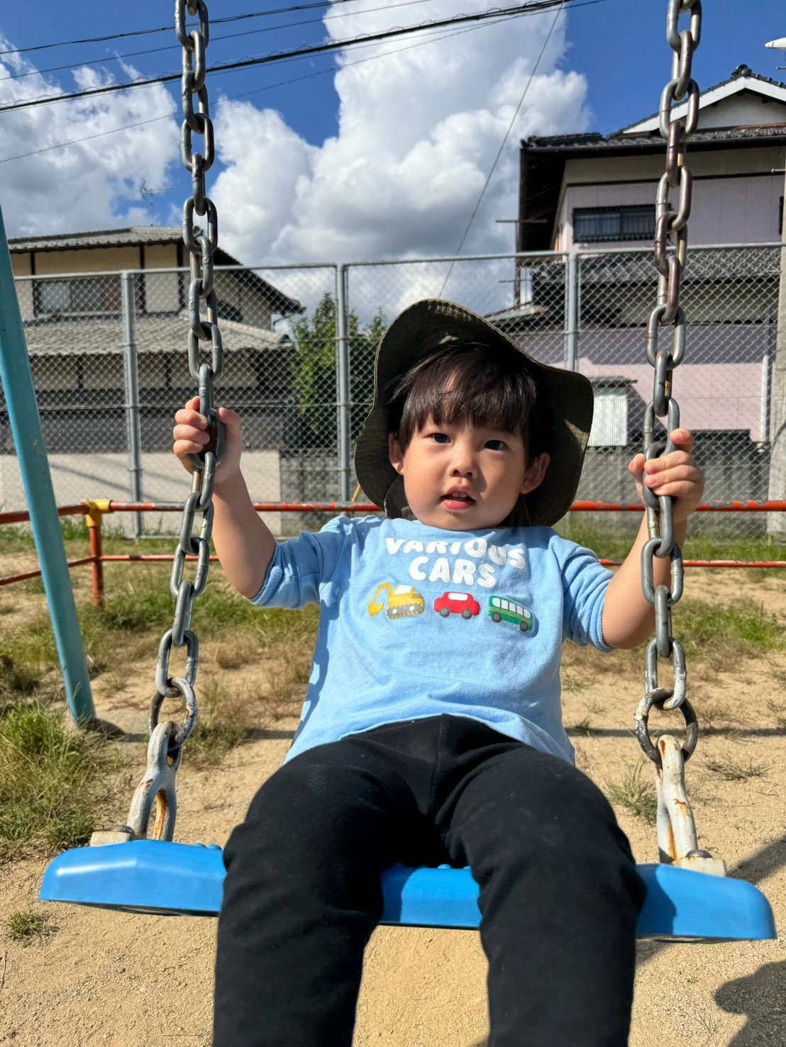 ブランコに座って両手で鎖を握る子ども
