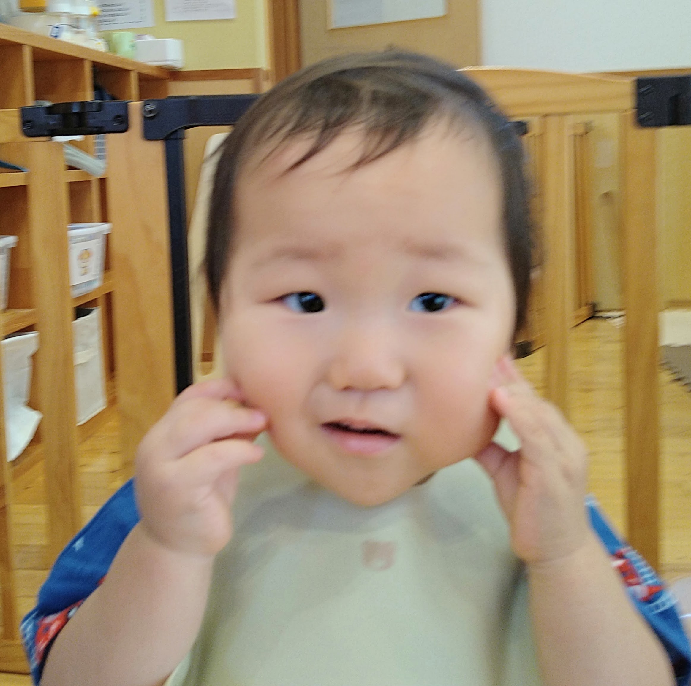 絵本に親しみ両手で頬に触れて表情を楽しむ子ども