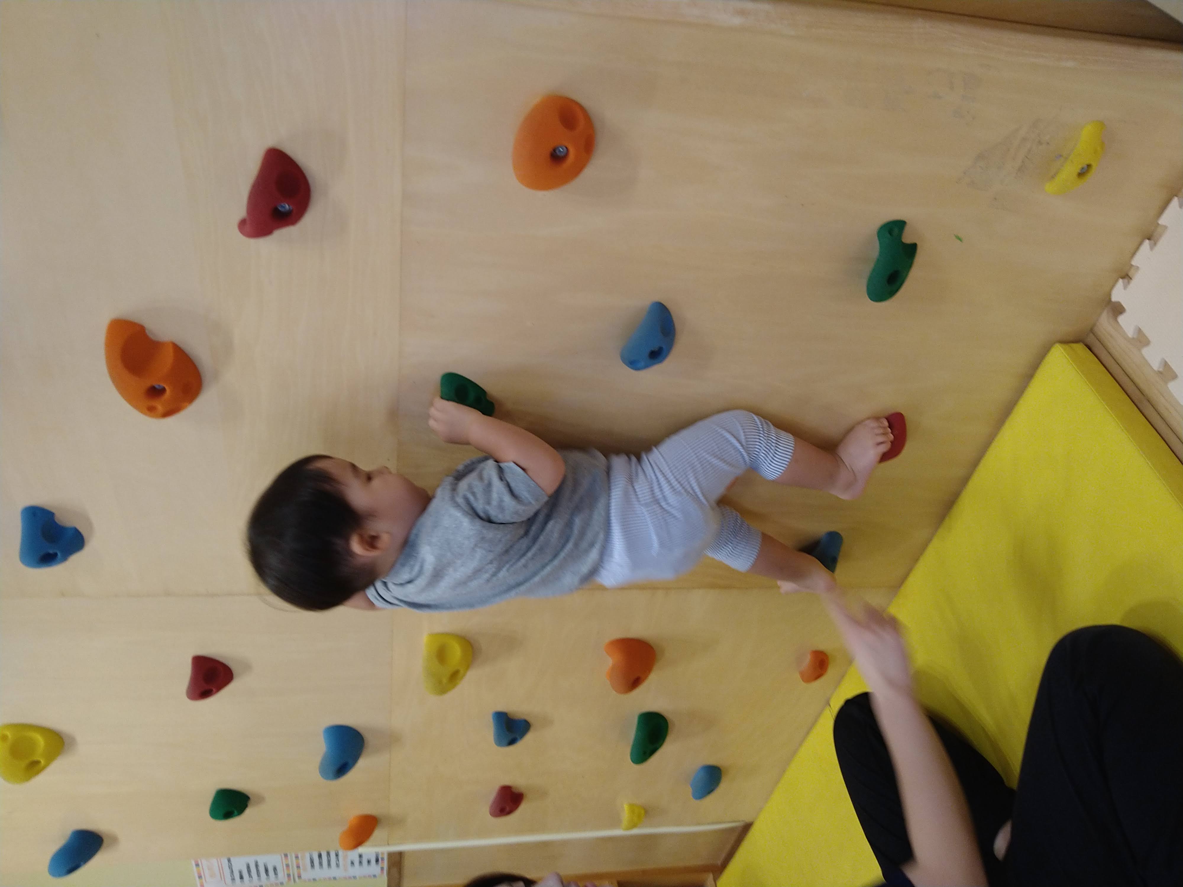 片足を高いホールドへ上げて体を支える子ども