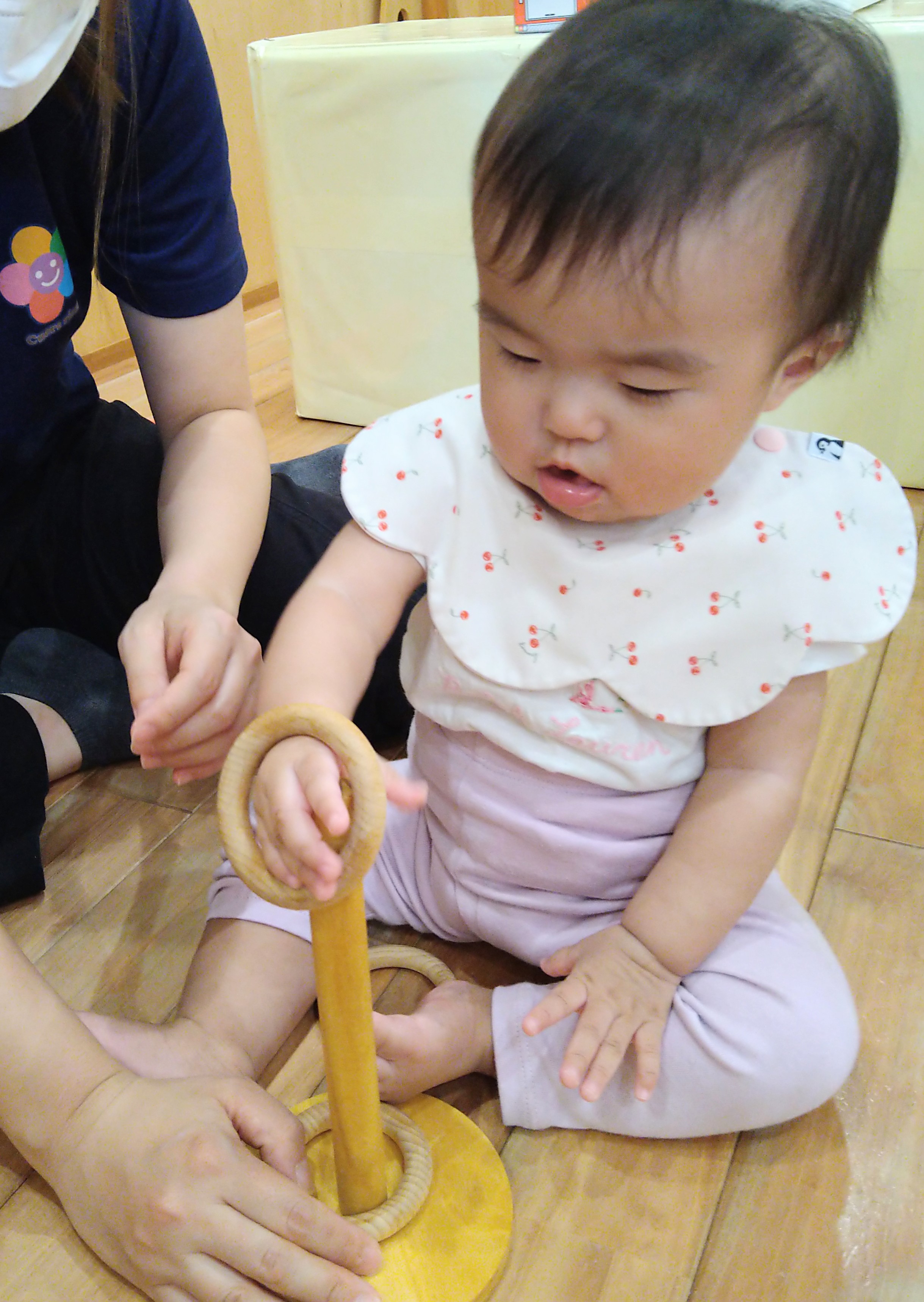 木の輪へ手を通して感触を確かめる子ども