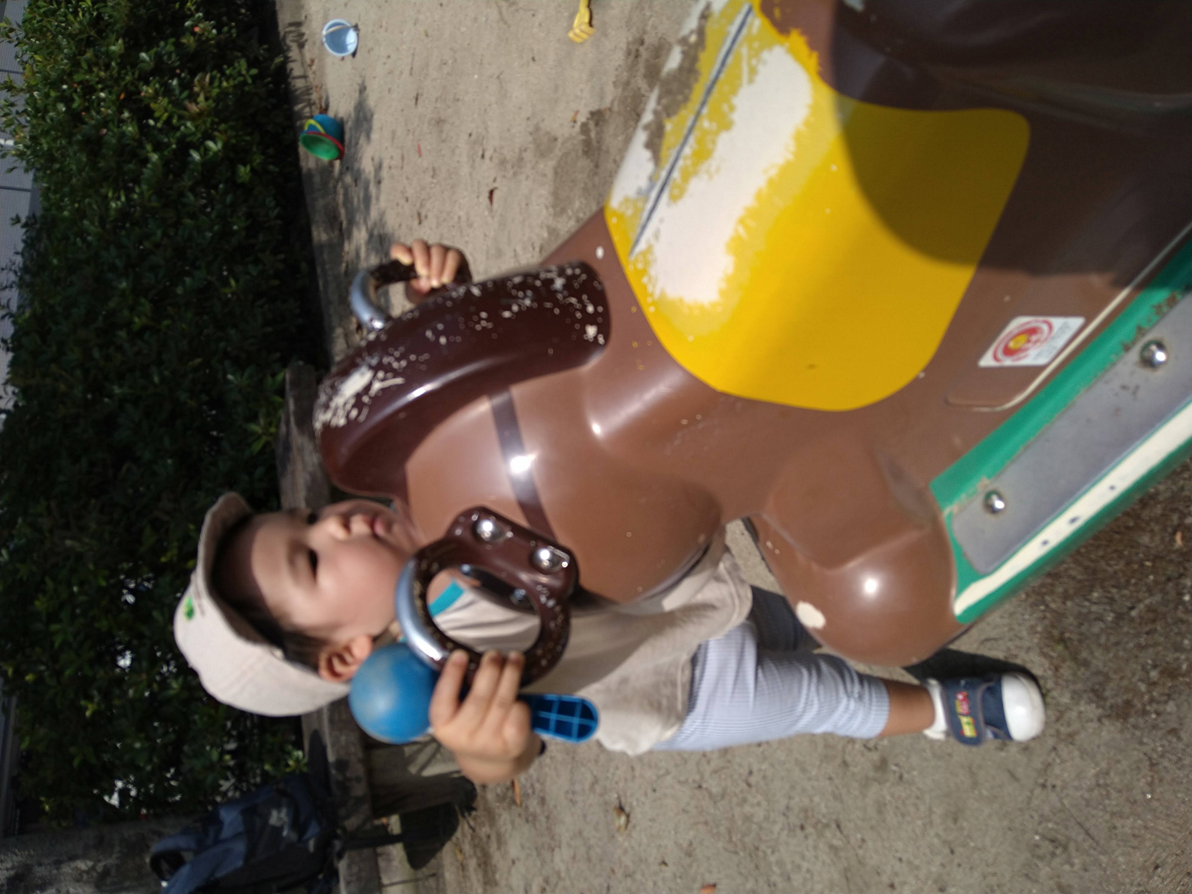 公園の固定遊具の持ち手を両手で握る子ども