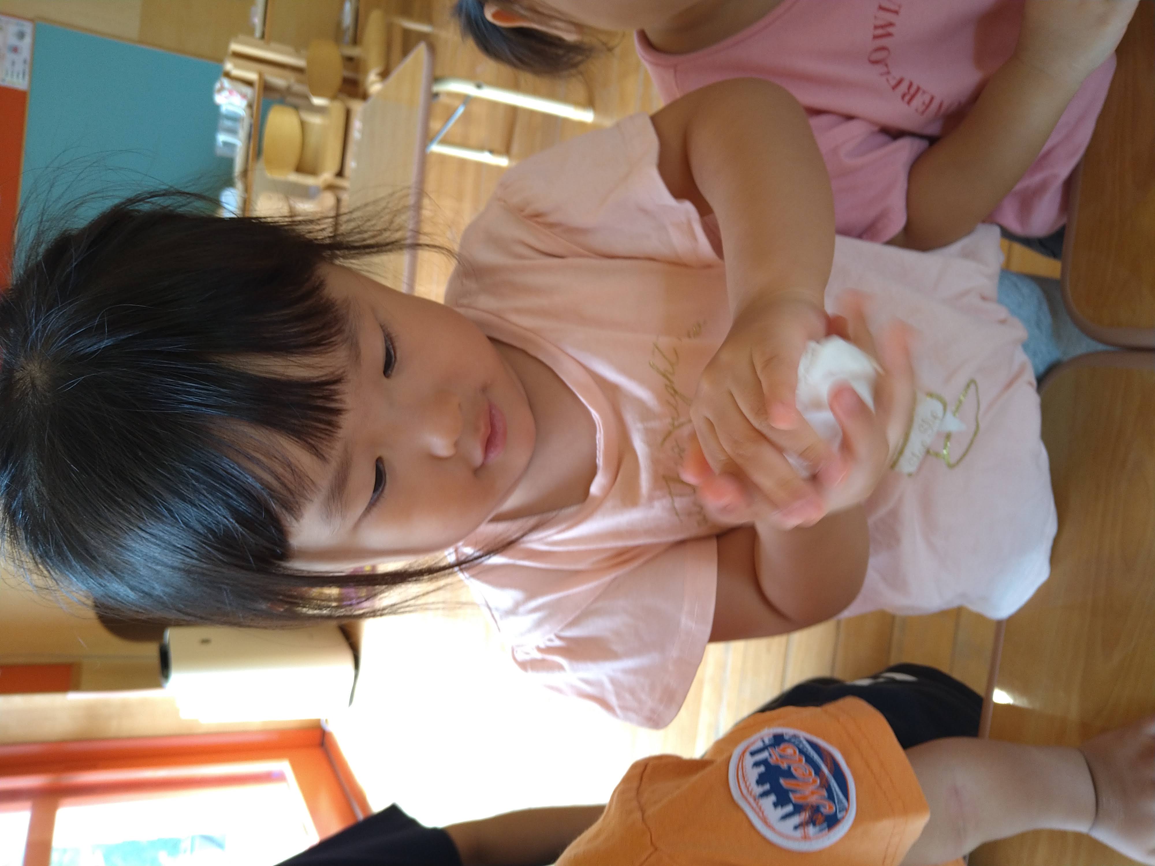 白い生地を両手のひらで丸める子ども