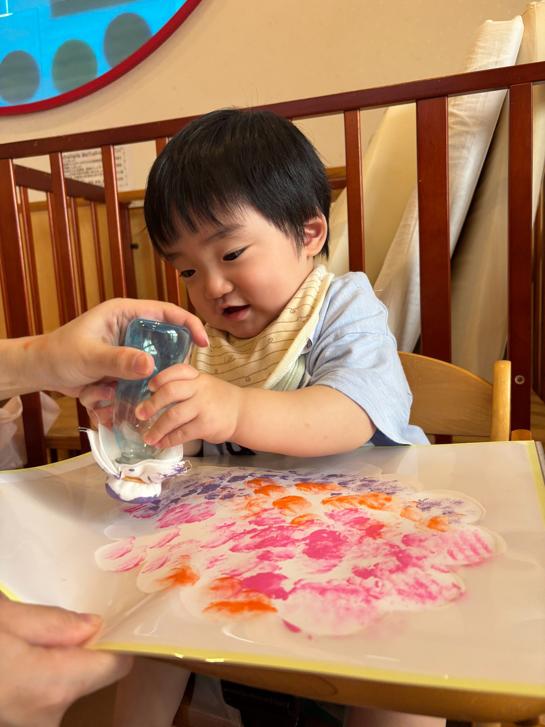 保育士に支えられながら両手で道具を押す子ども