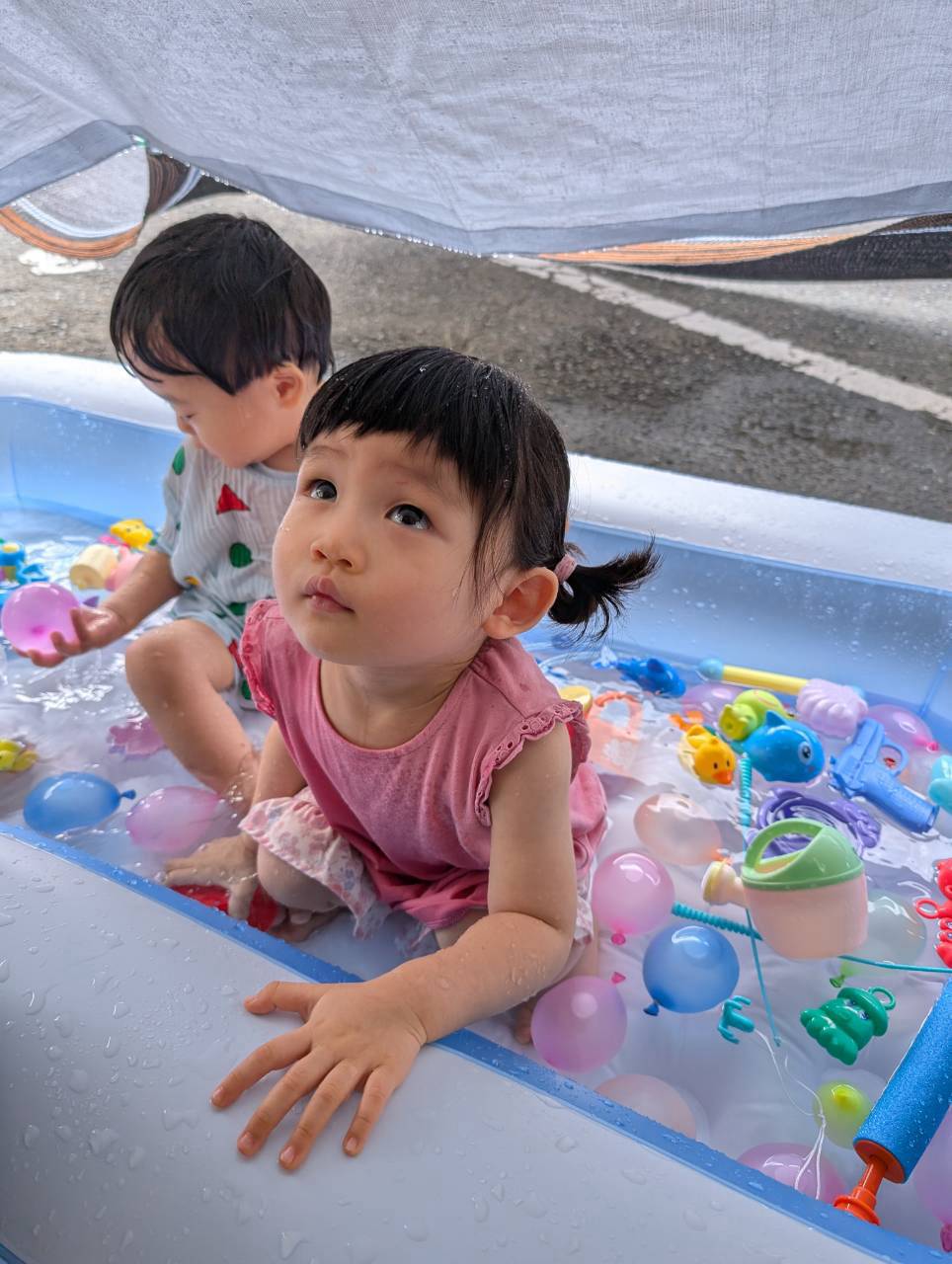 水面や浮かぶ玩具に触れて水遊びを楽しむ子どもたち
