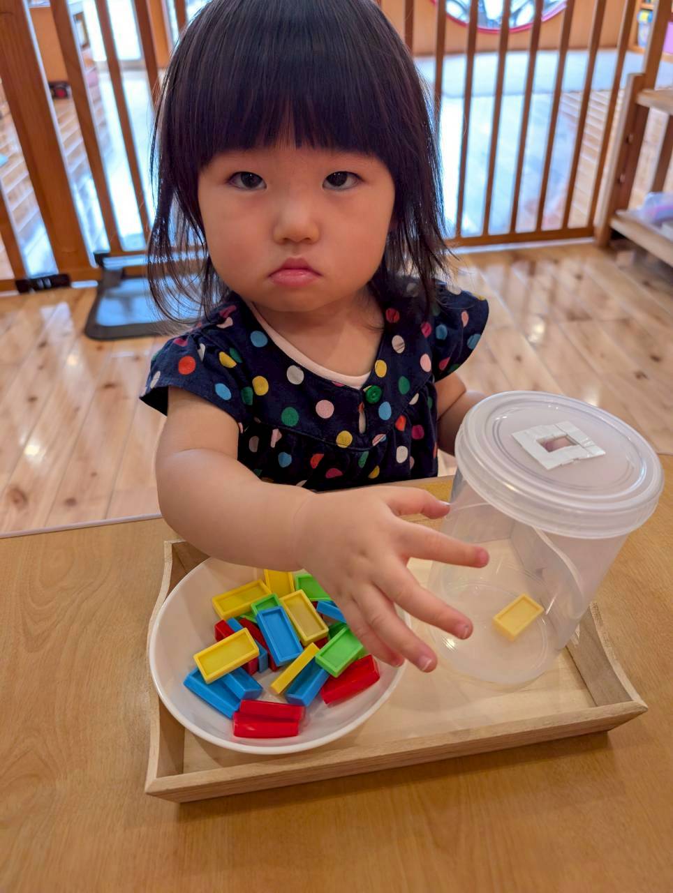 小さな色付きピースを皿と容器の間で移す様子