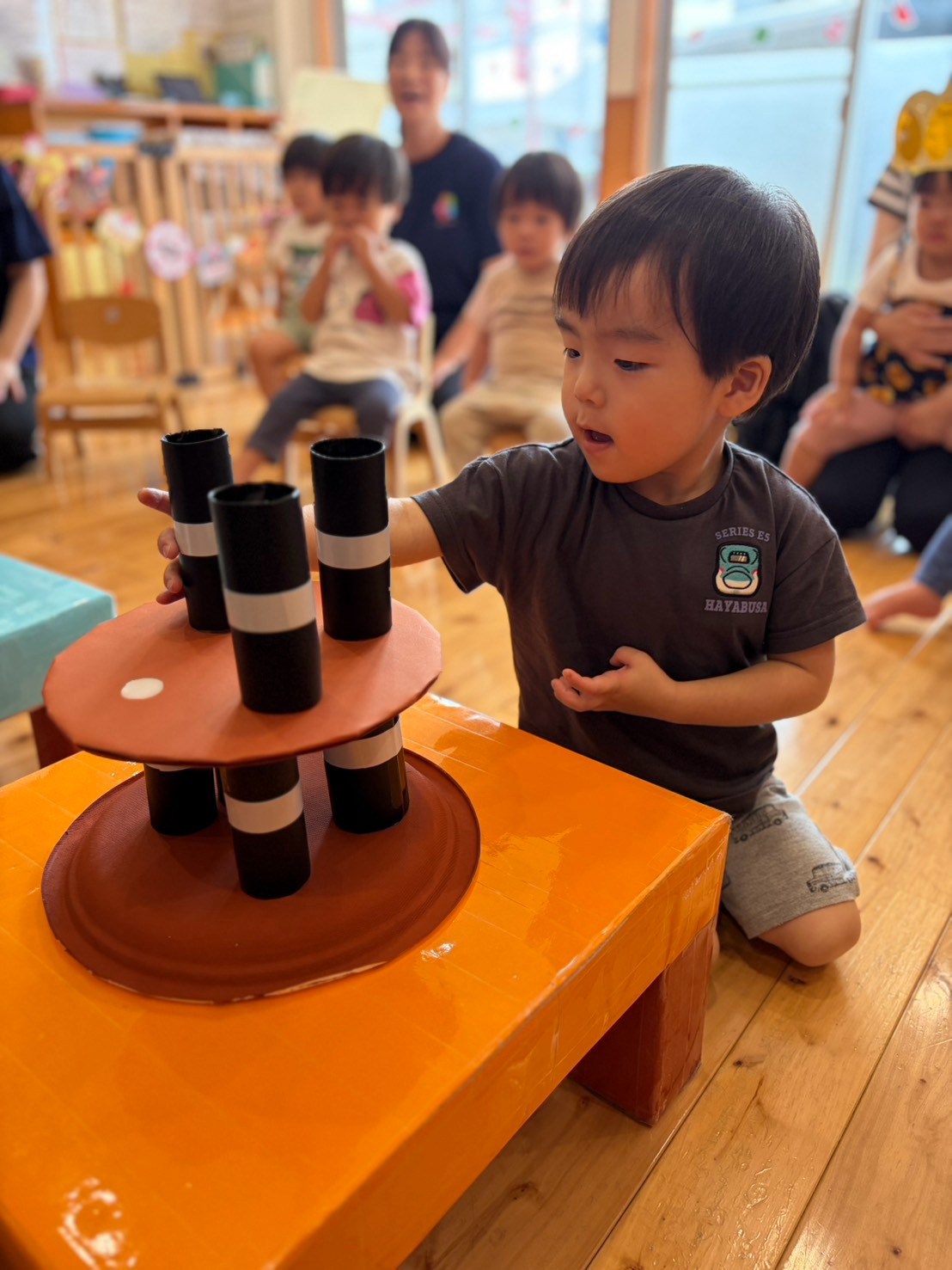 お誕生日会の遊びで筒を置く場所を考える子ども