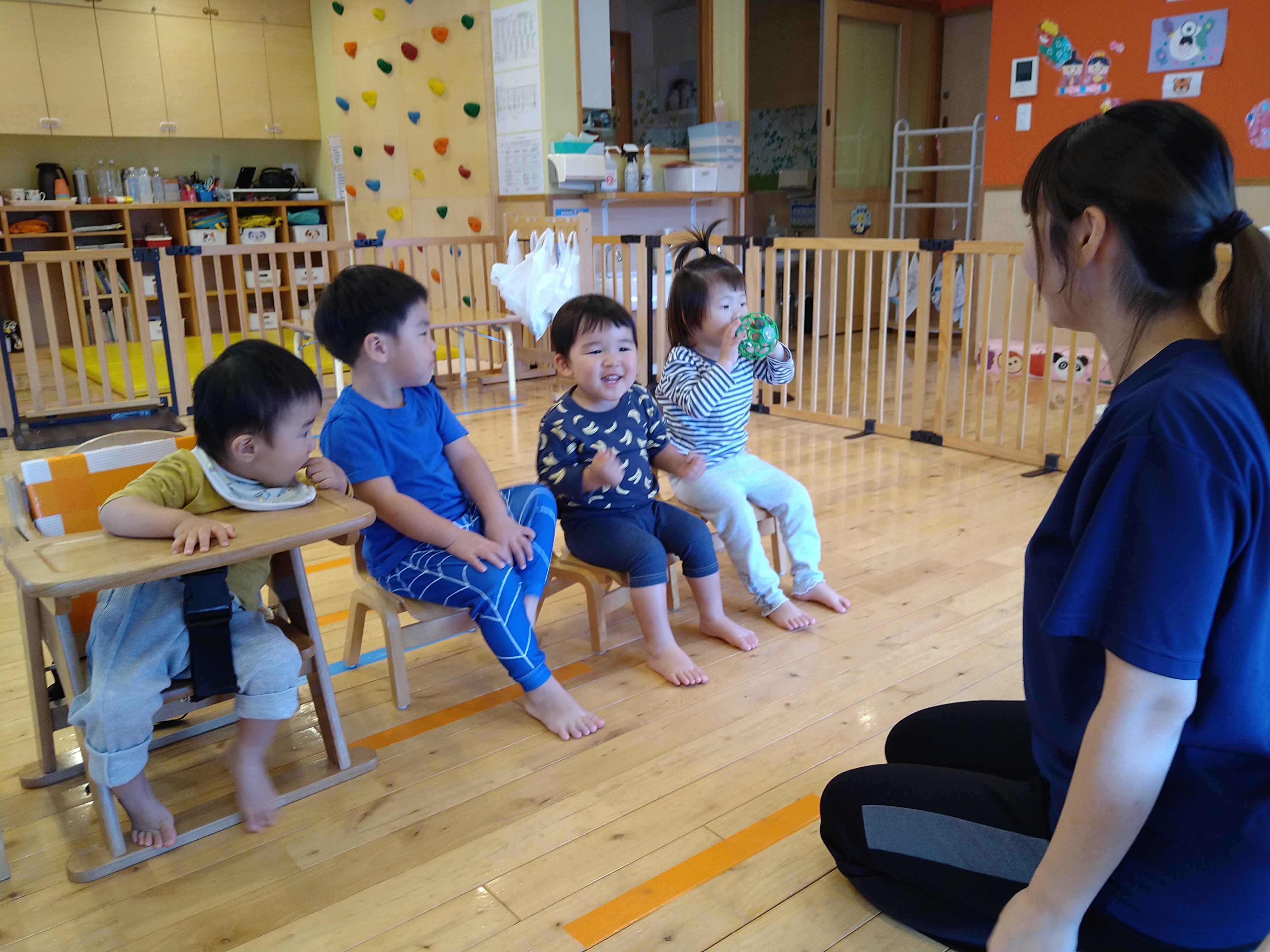 保育士へ顔を向けてお誕生日会に参加する子どもたち