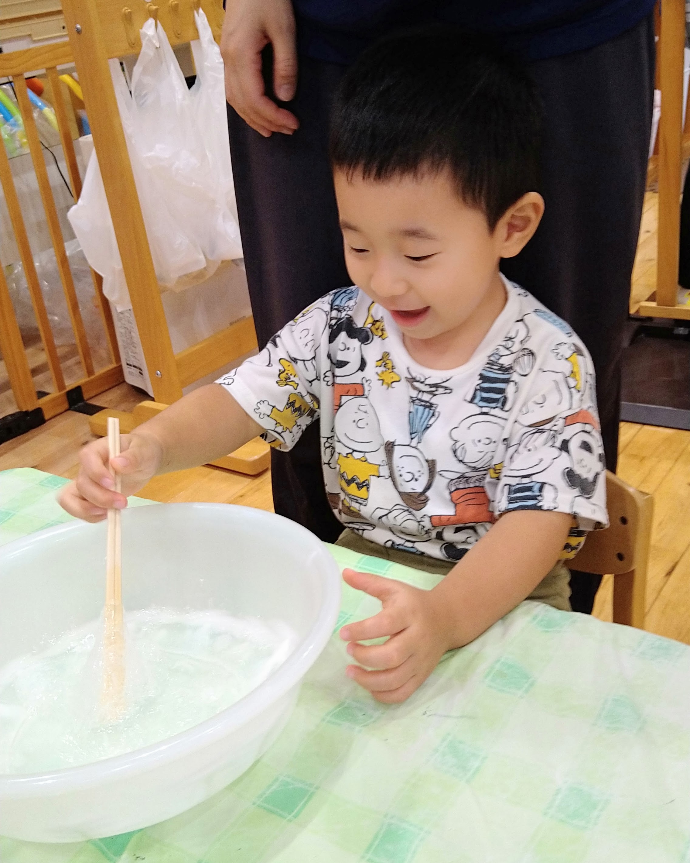 ボウルの中を道具で混ぜて変化を確かめる子ども