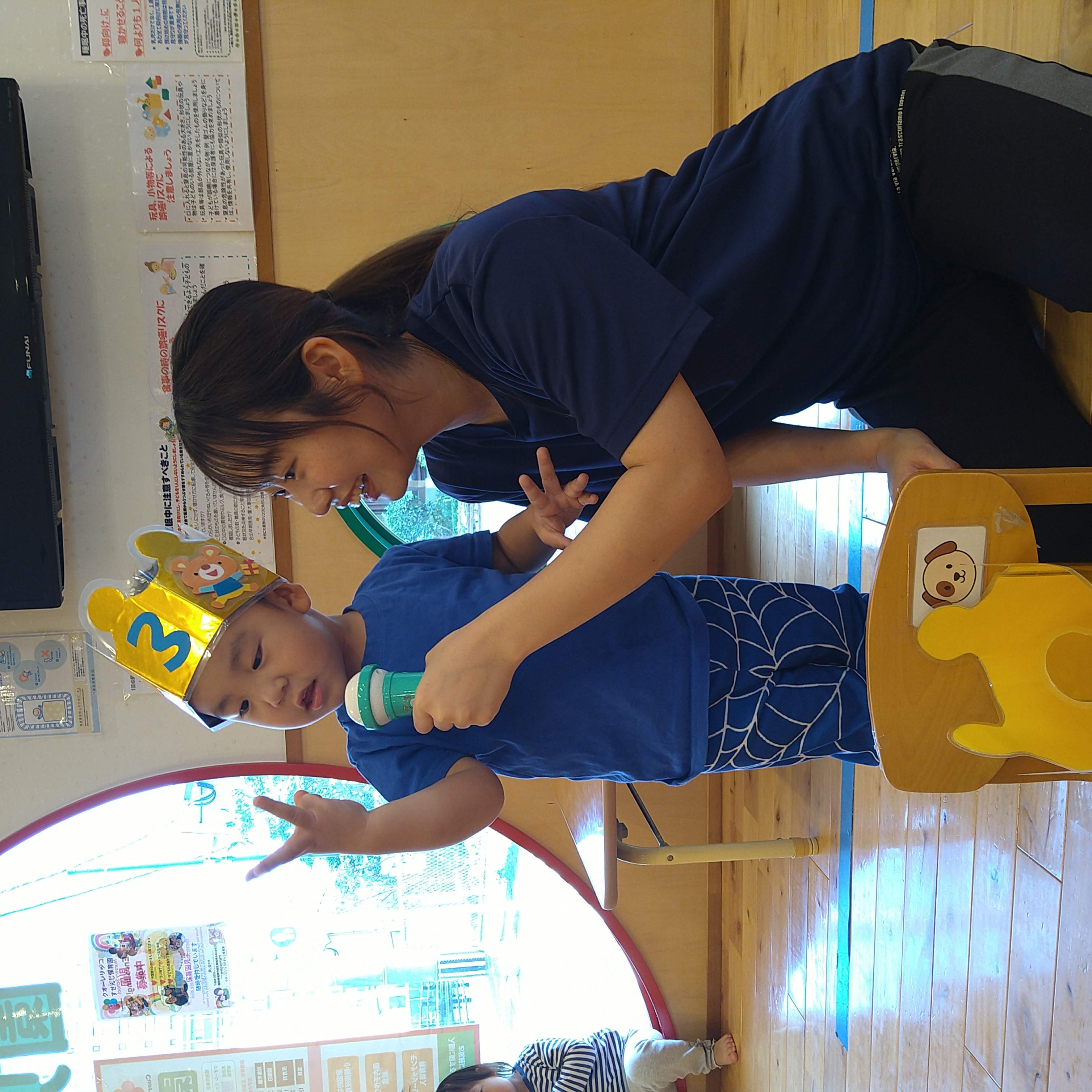 お誕生日会で保育士と一緒にマイクへ向かう子ども
