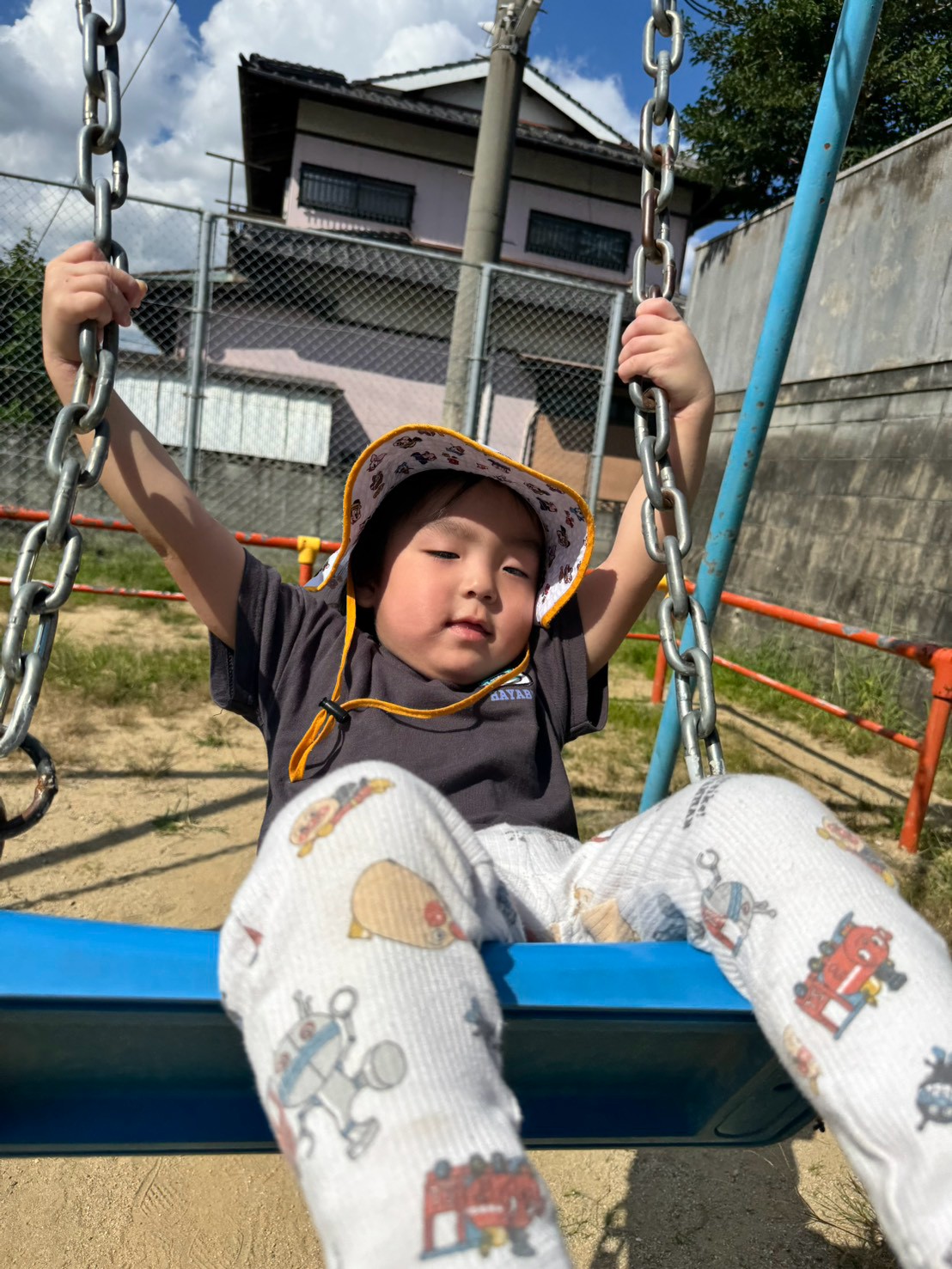 ブランコの鎖を両手で握って揺れを楽しむ子ども