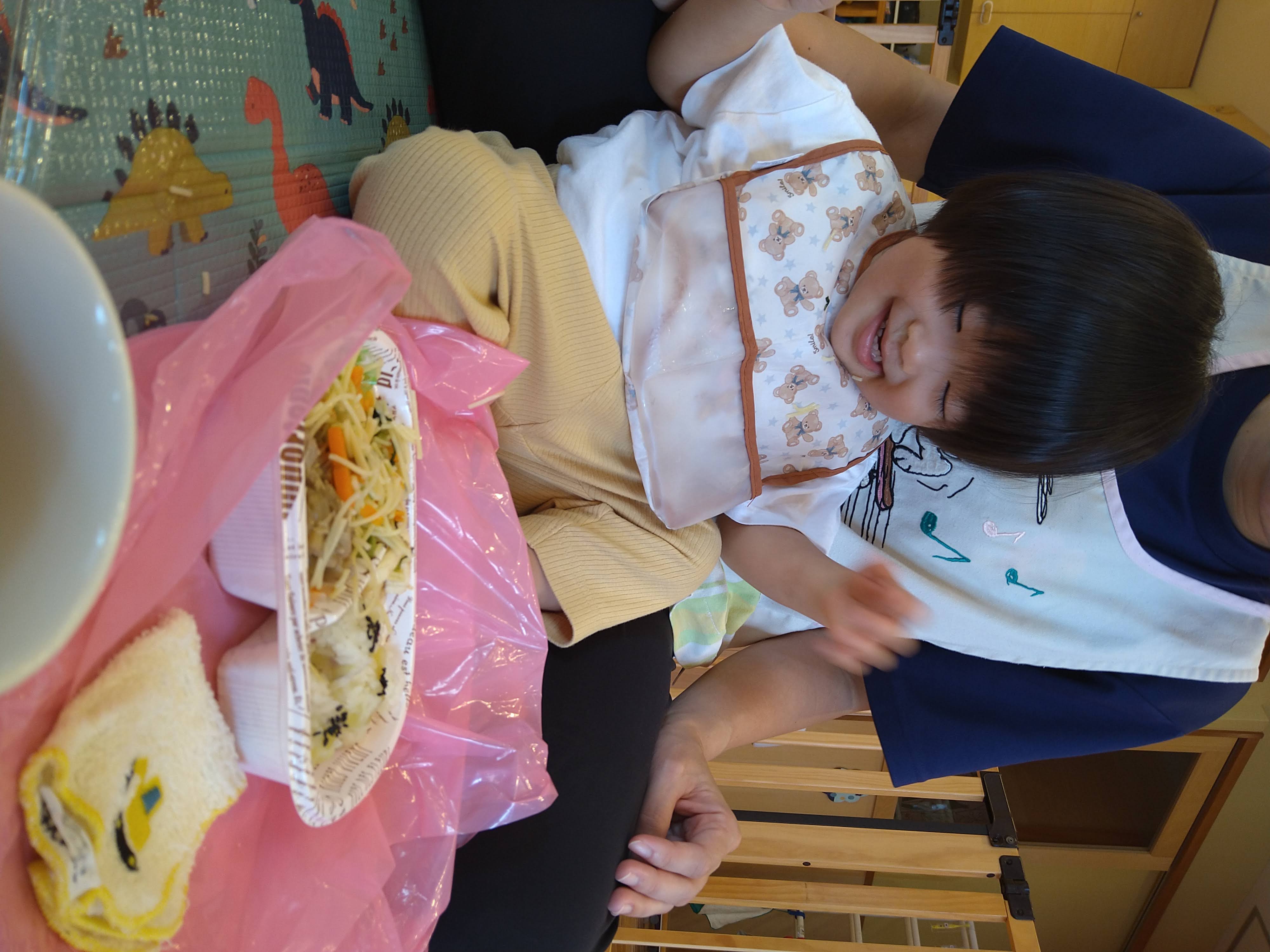 給食を前に笑顔で両手を動かす子ども