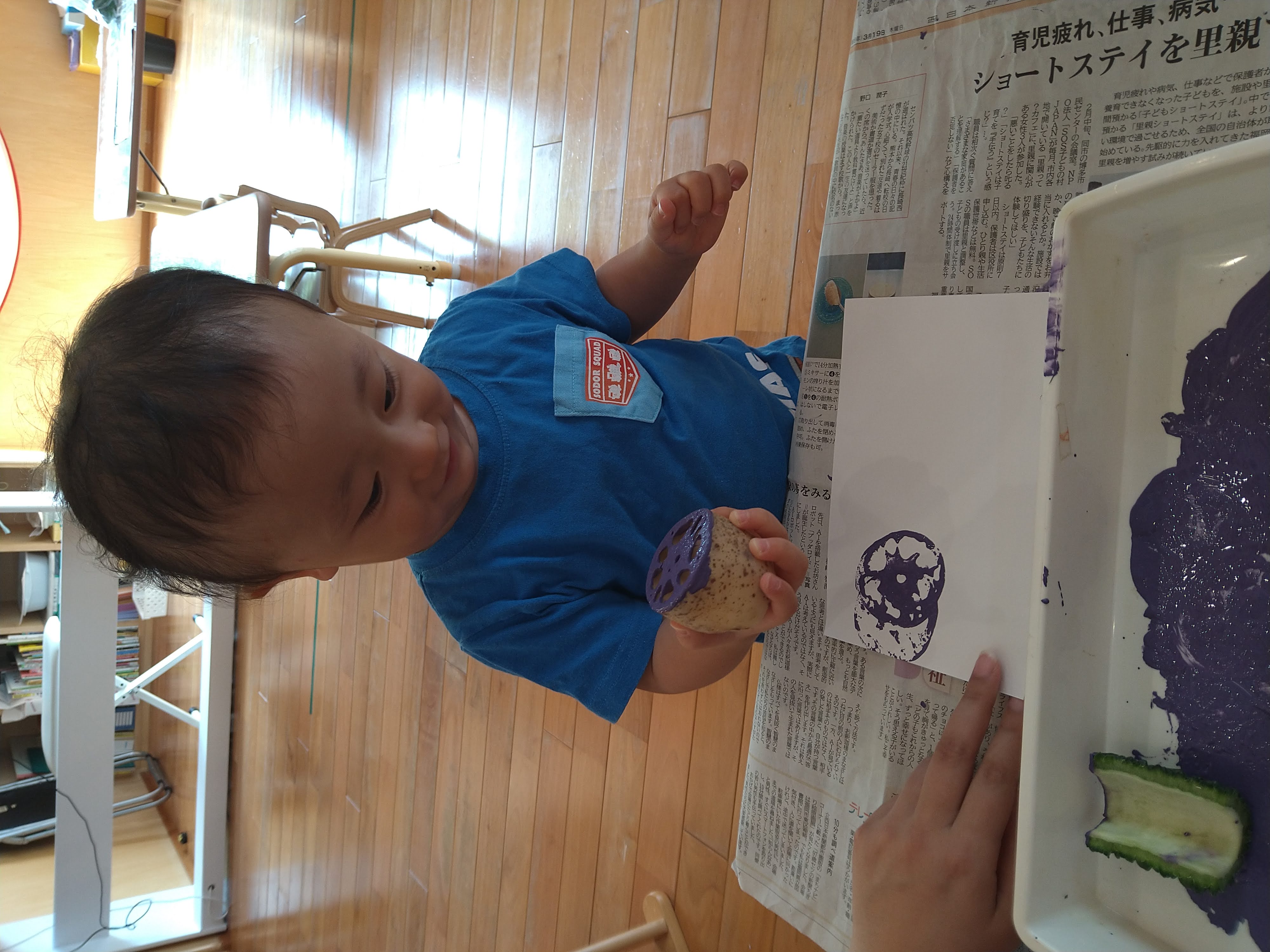 れんこんを持ち上げて紙に写った紫色の模様を見る子ども