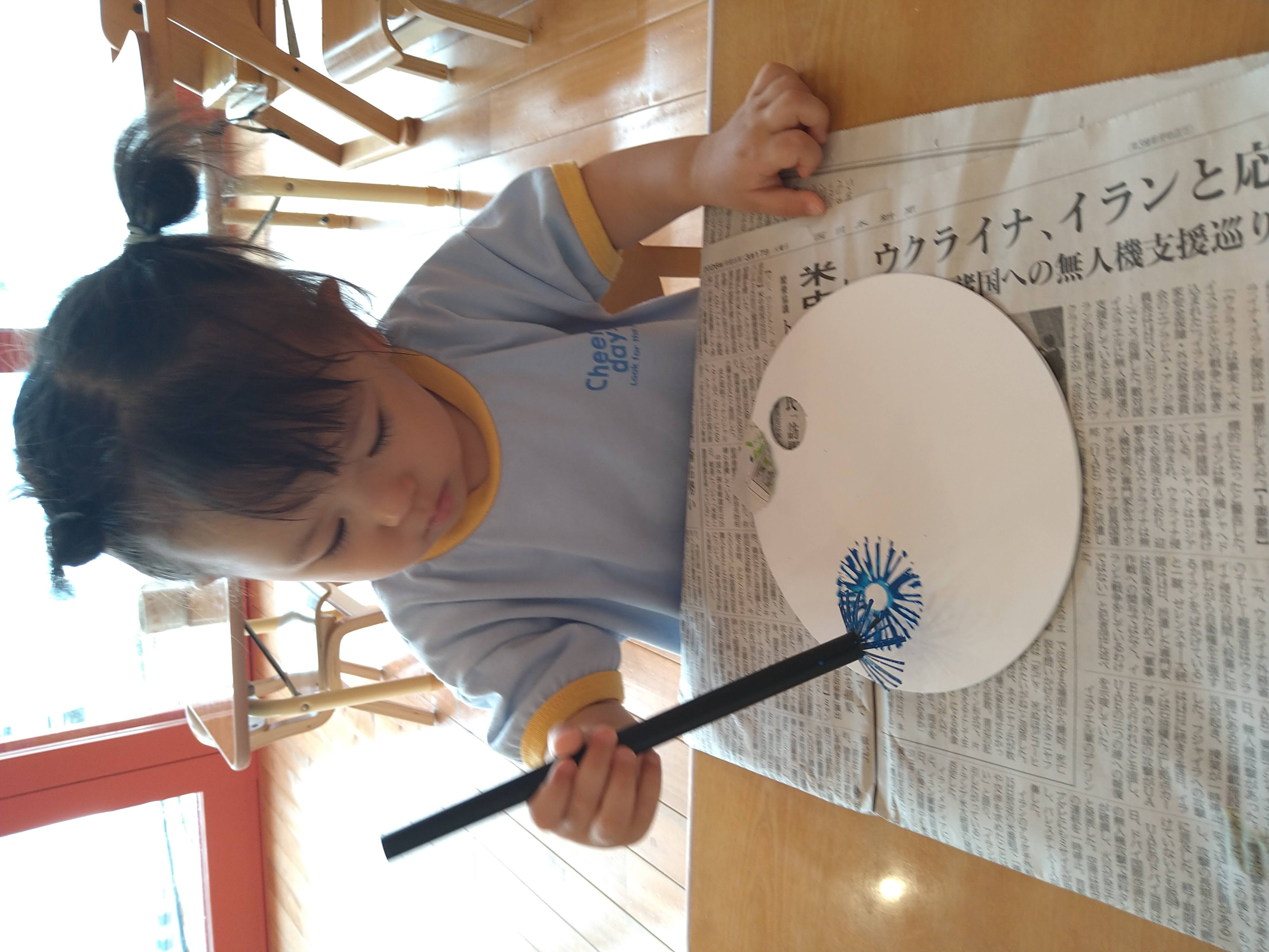 ストローを握り青い絵の具で模様をつける子ども