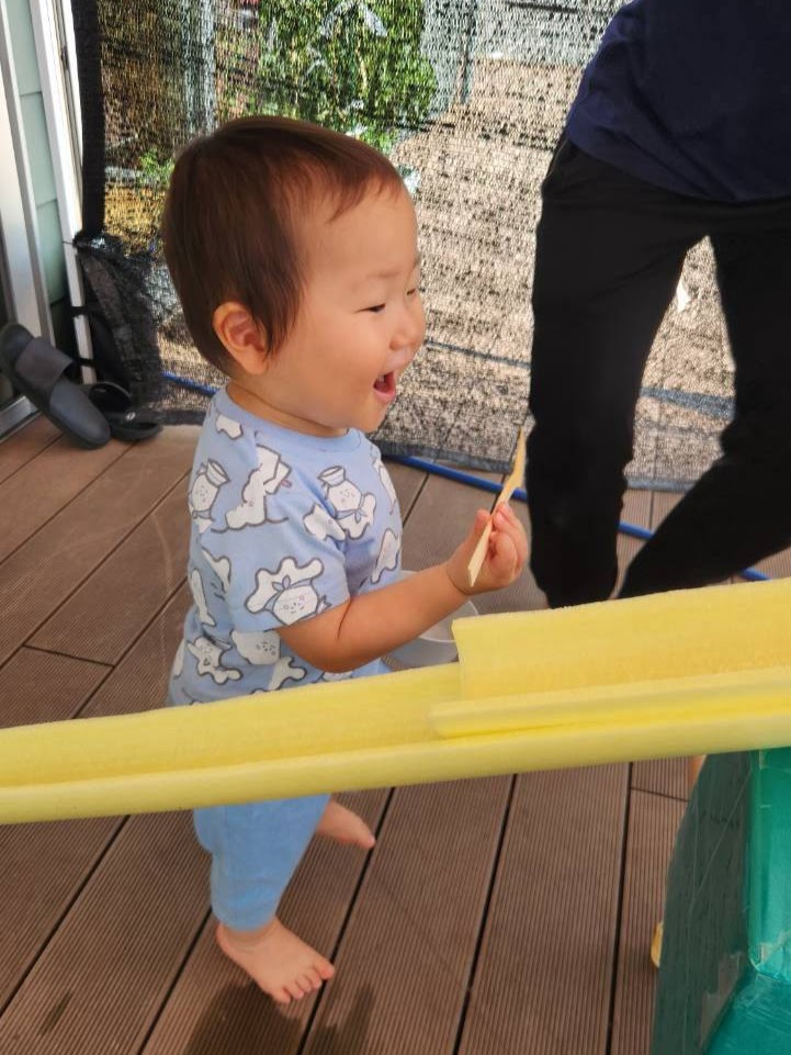 そうめん流しの道具を持ち笑顔を見せる子ども