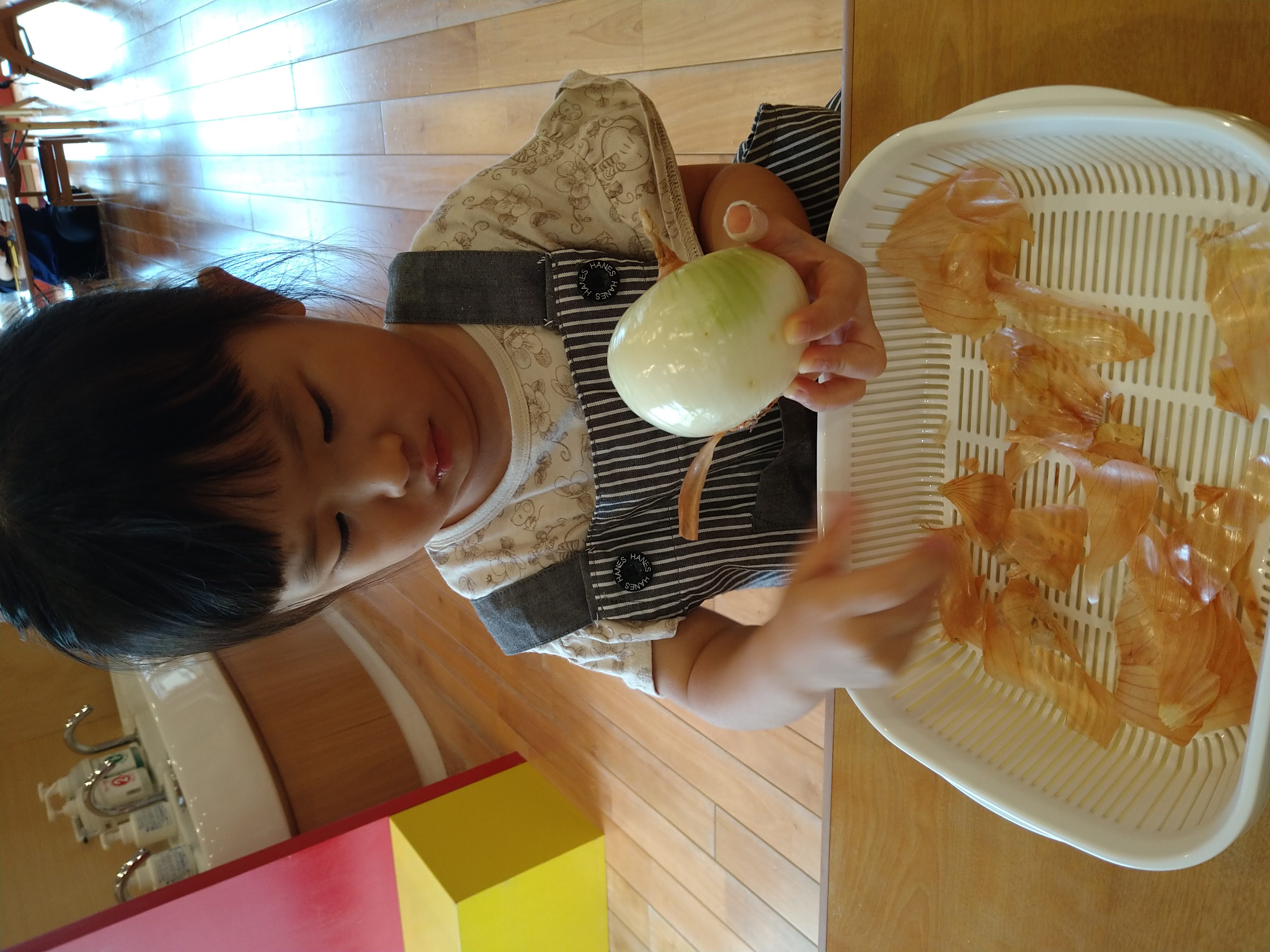 皮をむいて白くなった玉ねぎを見つめる子ども