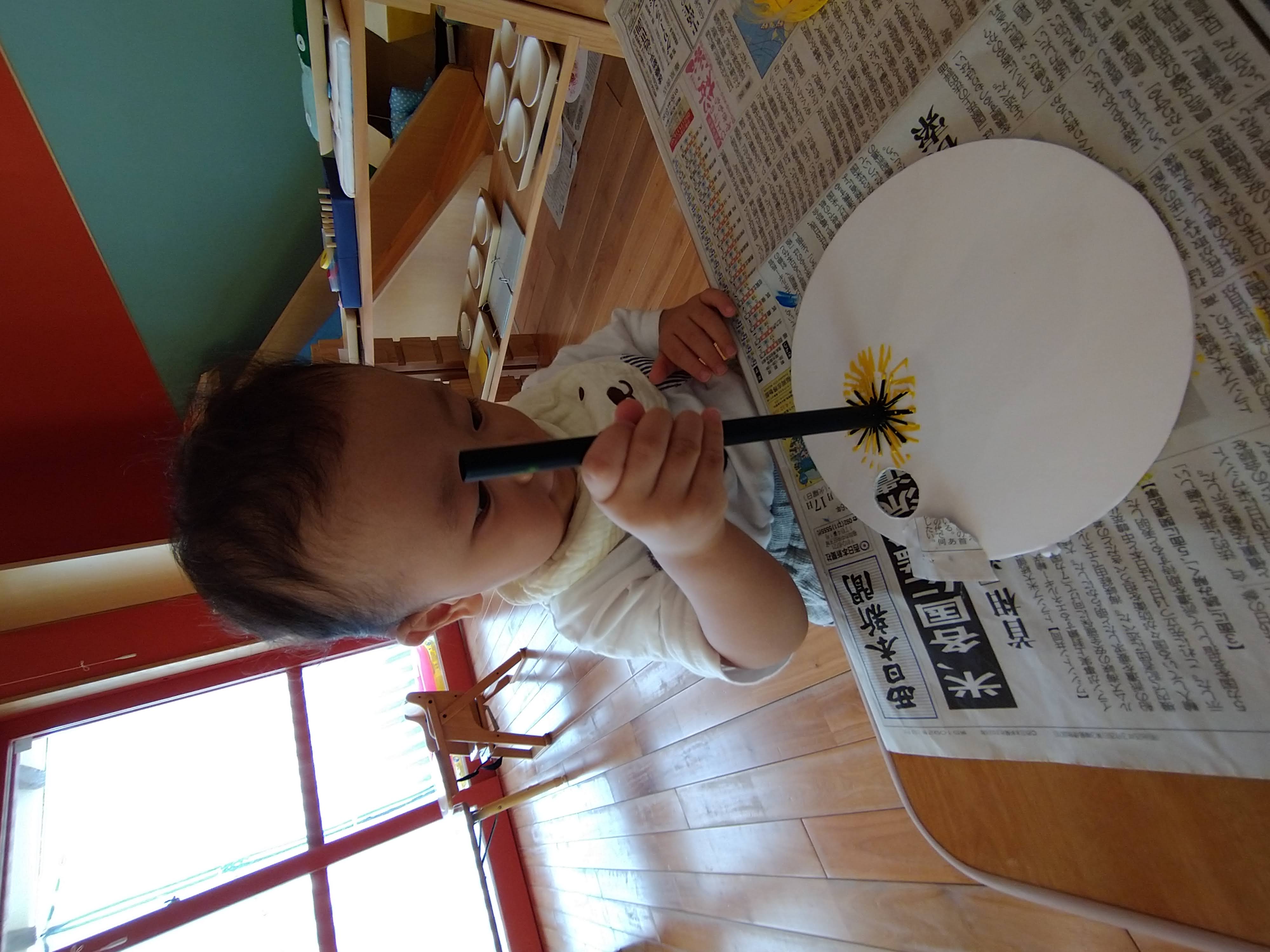 黄色い絵の具をつけたストローを画用紙へ押す子ども