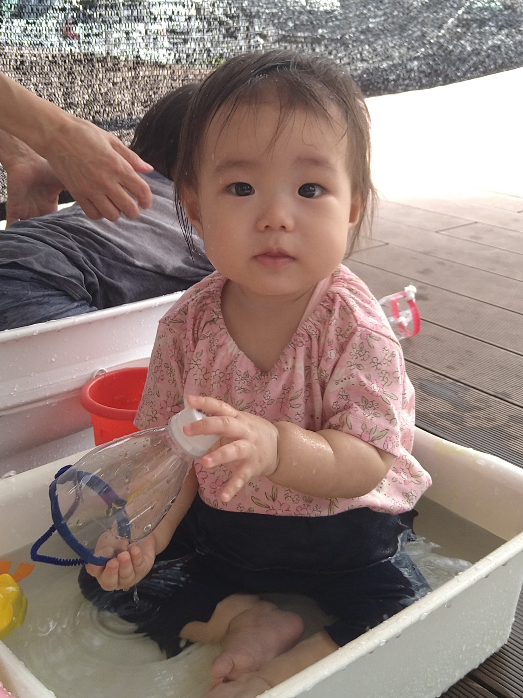 透明な容器を持って水の感触を確かめる子ども