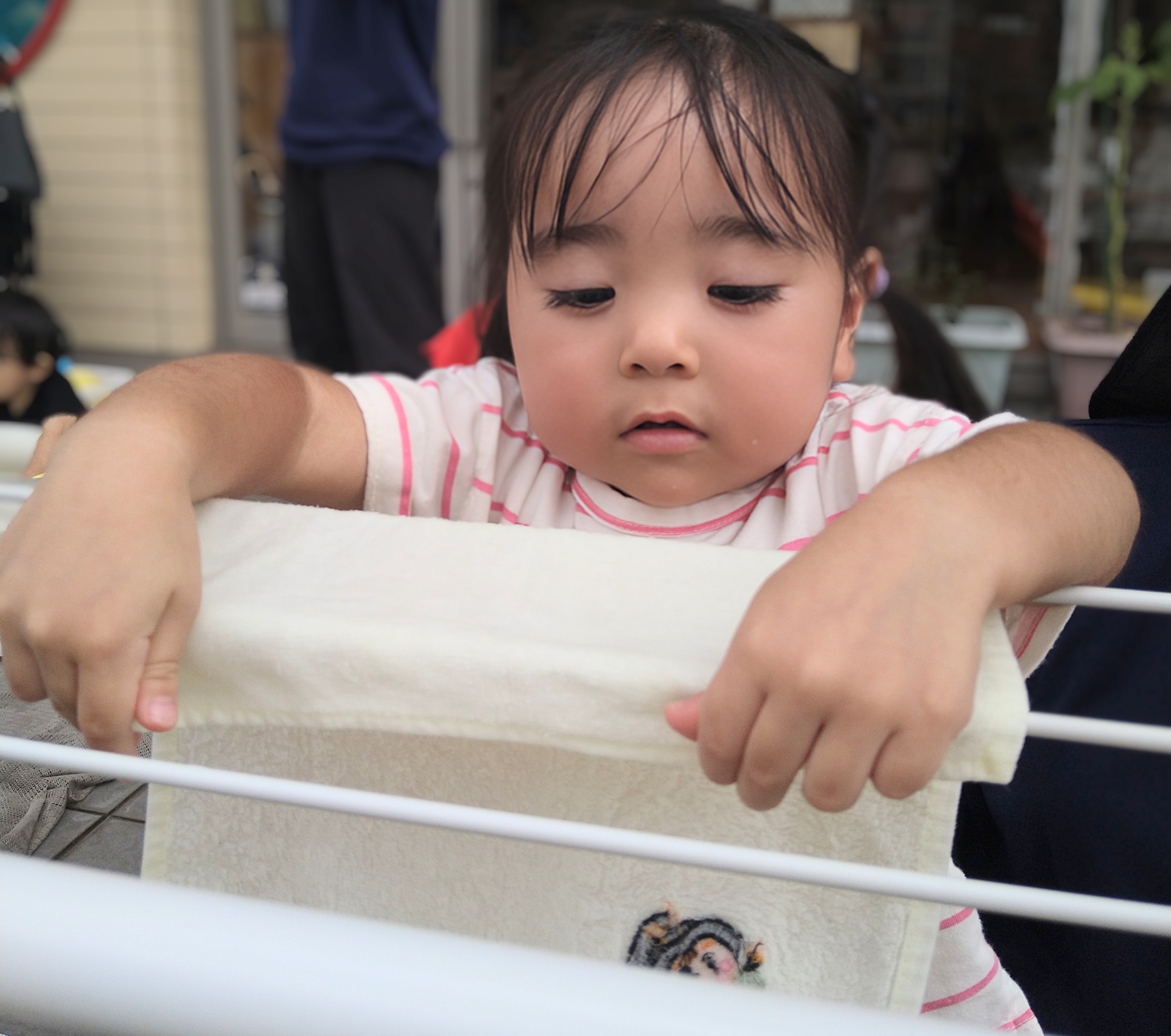 濡れた布を両手で持って物干しへ広げる子ども