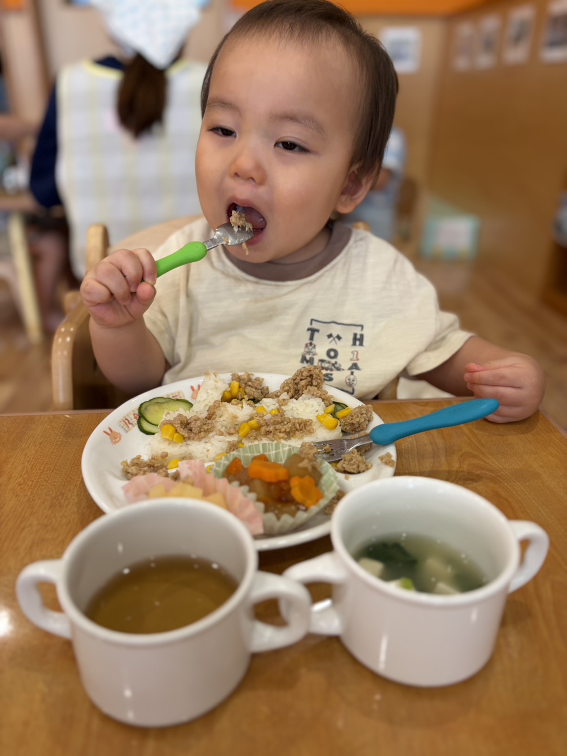 スプーンで給食を口へ運ぶ子ども