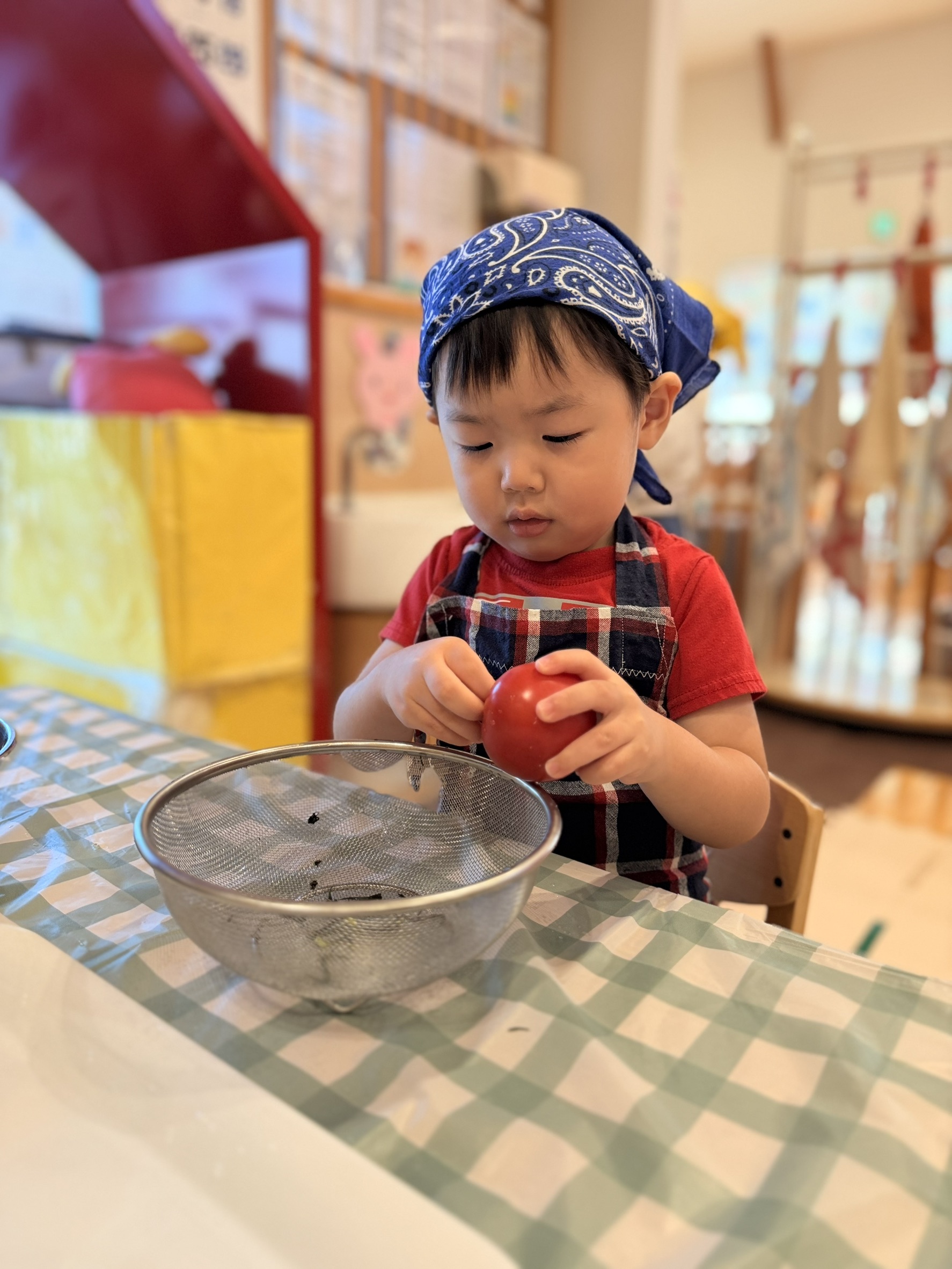 洗ったトマトを持ちざるの位置を確かめる子ども